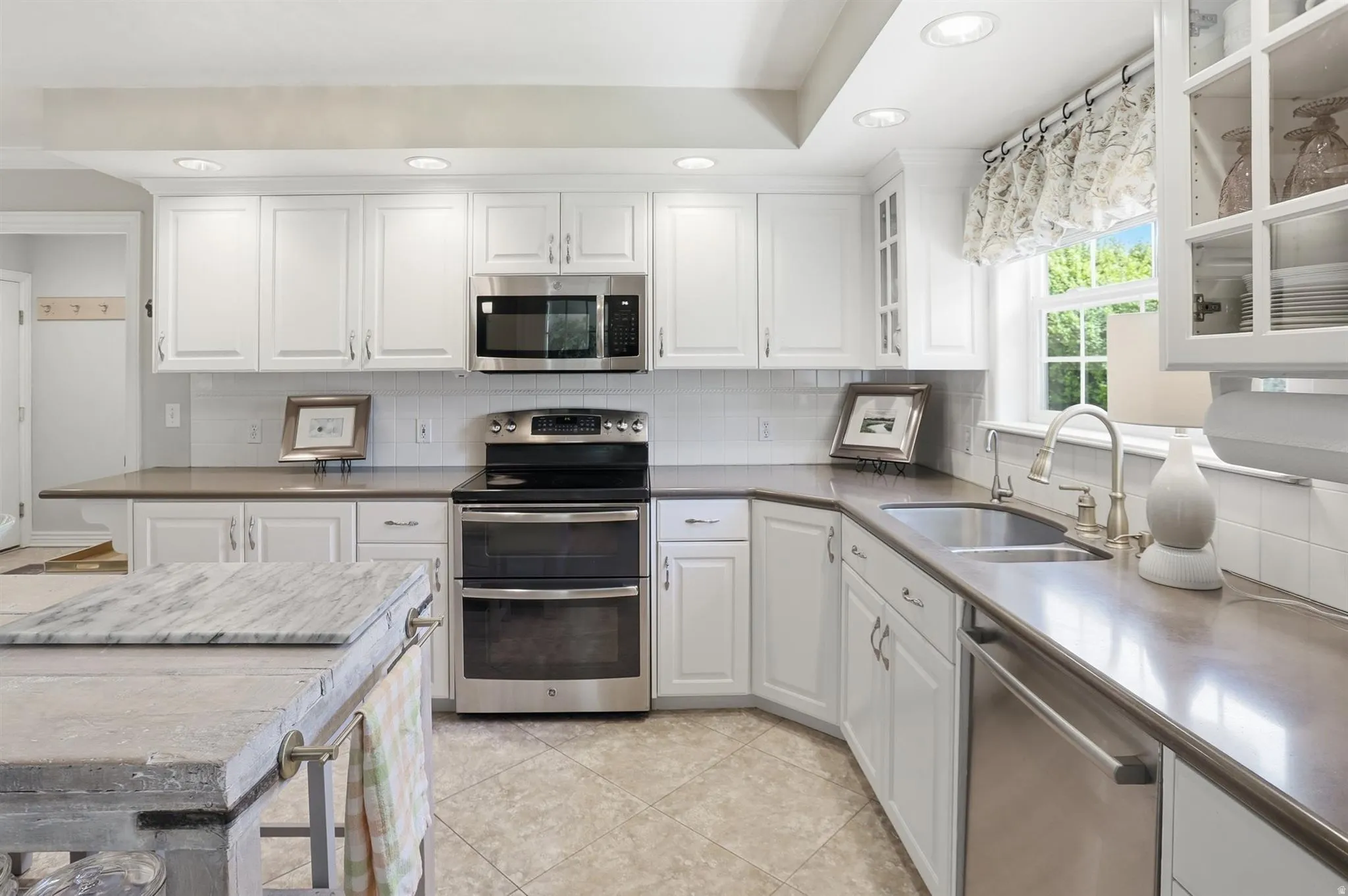 Kitchen featuring white shaker-style cabinetry, stainless steel appliances, a subway tile backsplash, and recessed lighting