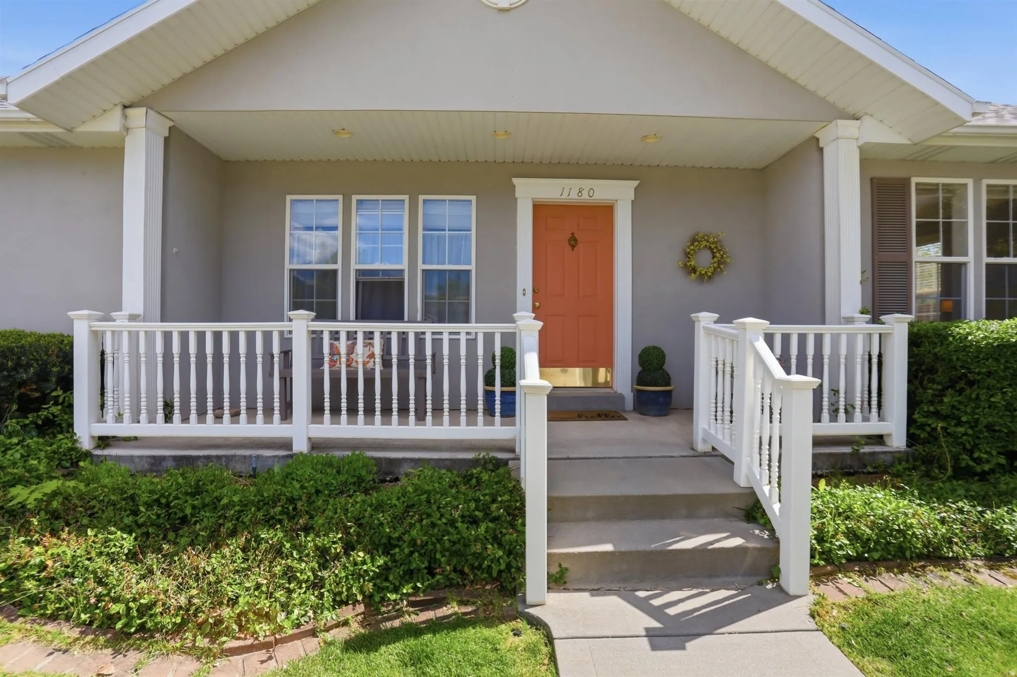 Inviting front porch with a vibrant pink entry door, white baluster railings, and covered porch
