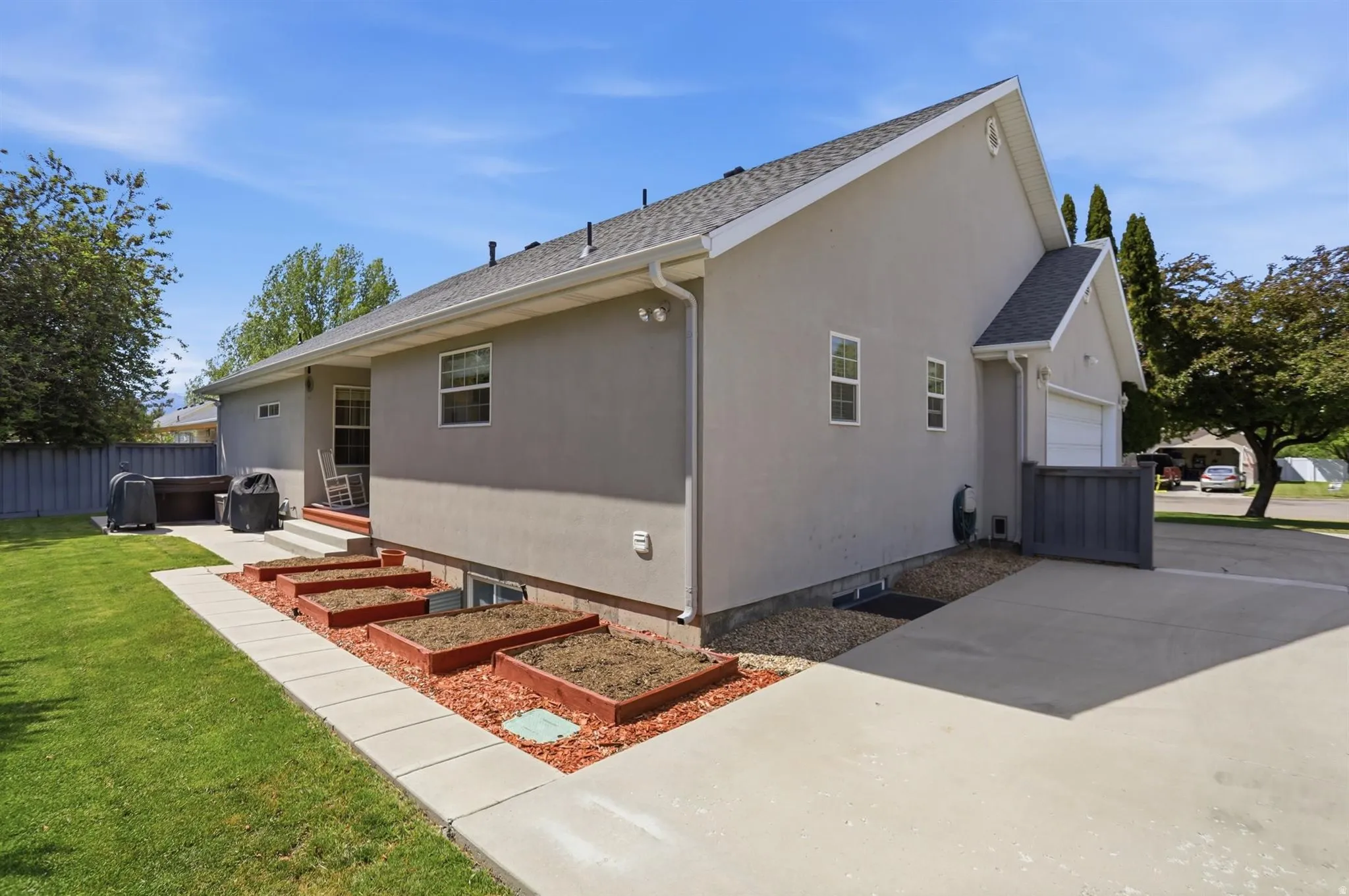 Rear exterior with a concrete patio, privacy fence, and multiple raised garden beds