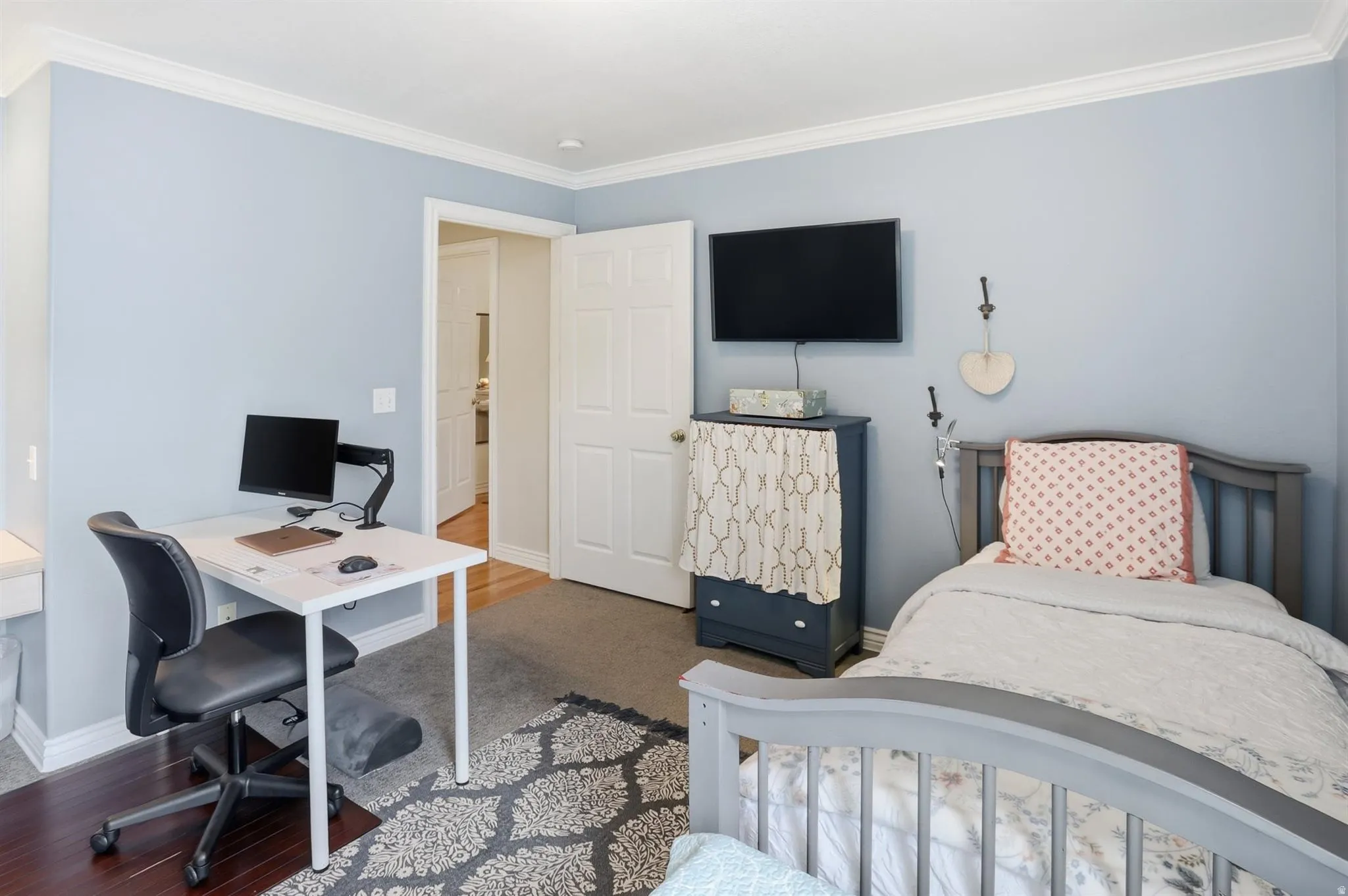 bedroom 2 featuring light blue walls, white crown molding, and a combination of wood-finish flooring and carpet