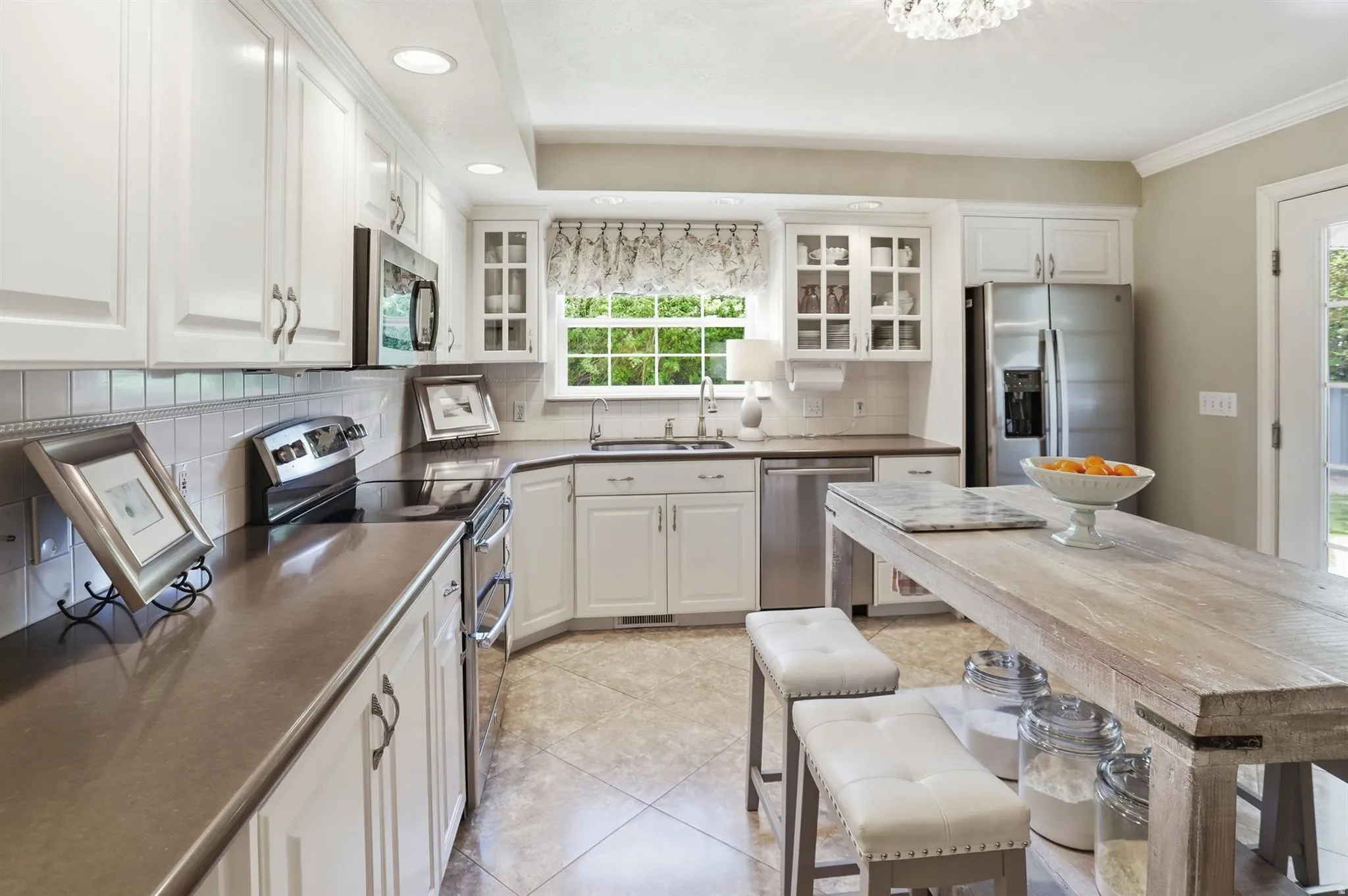 Kitchen featuring white cabinetry, stainless steel appliances, dark countertops, tiled flooring, and a large window