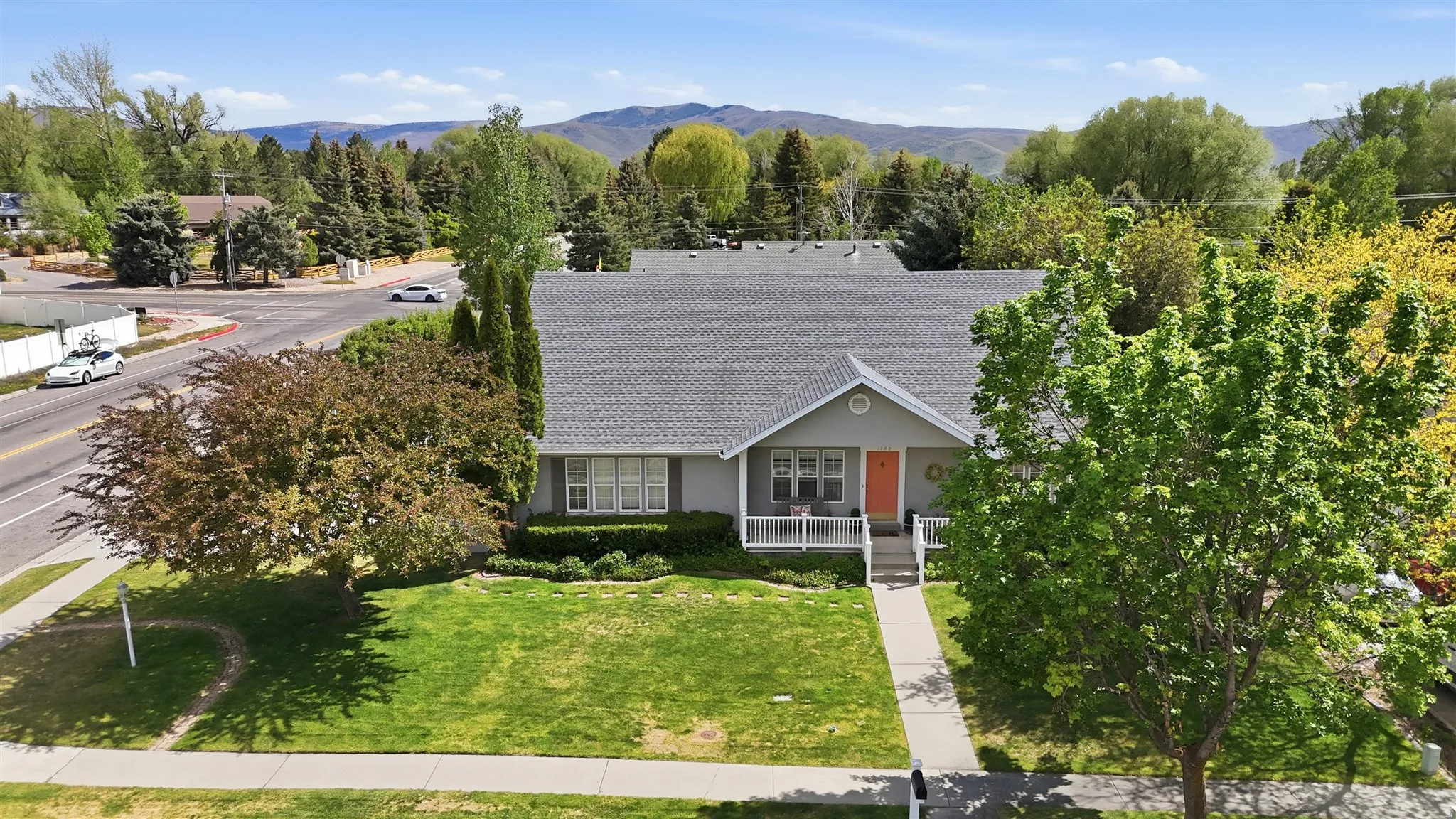 Rambler residence featuring a gray exterior, a prominent front porch with white railing, and an orange entry door