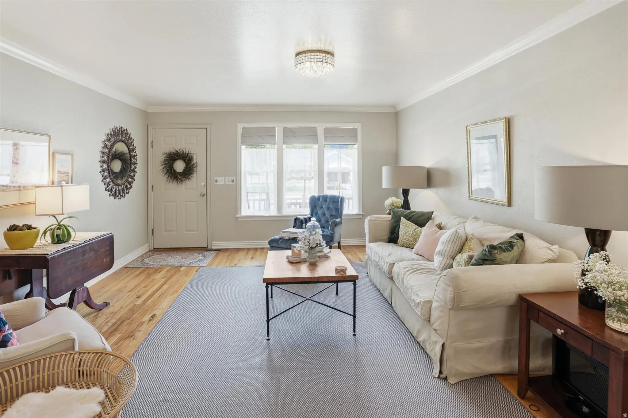 Living room featuring wood-finish flooring, crown molding, and multiple windows