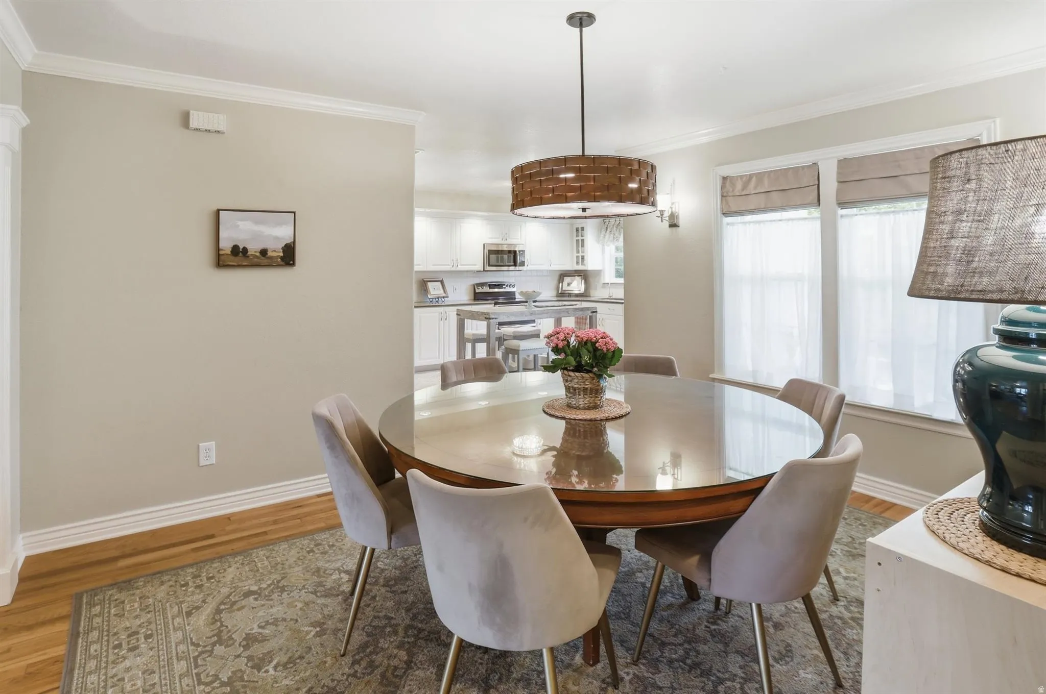 Dining area featuring wood-finish flooring, crown molding, and a woven-style pendant light fixture