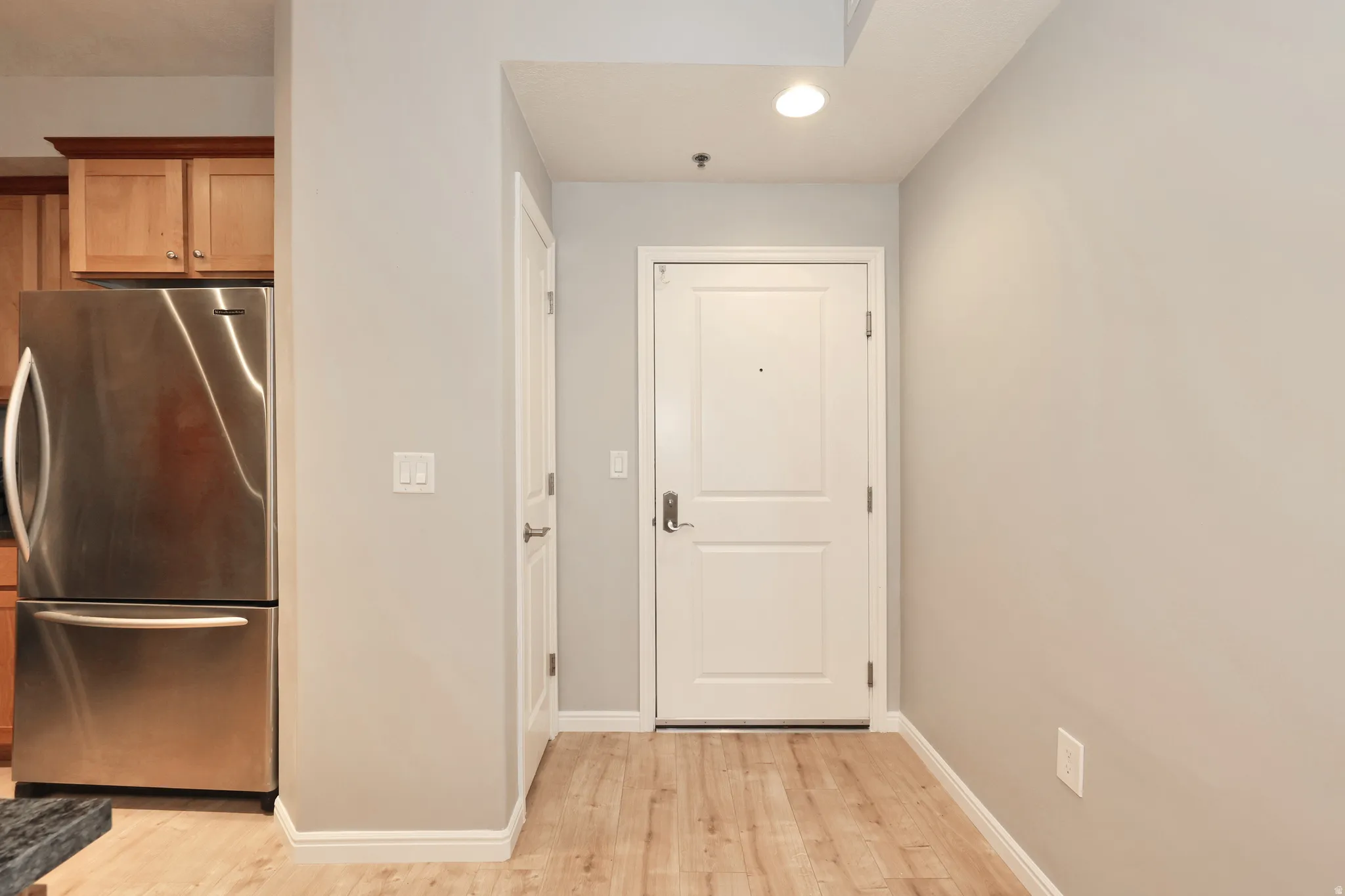 Entryway featuring light wood-finish flooring, white trim, and a contemporary white door