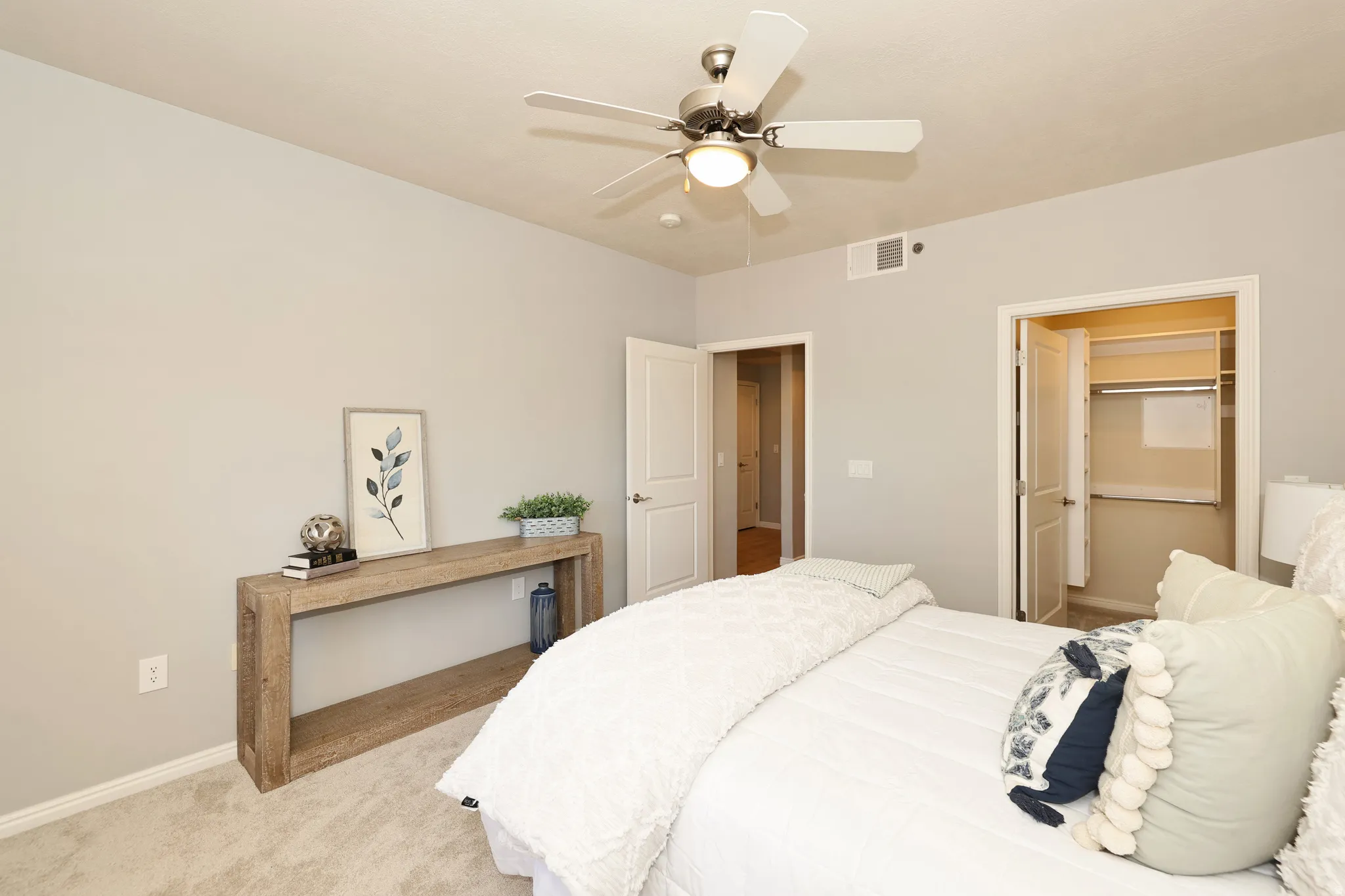 Carpeted bedroom featuring a ceiling fan with integrated lighting, a built-in closet with shelving and hanging rods, light gray walls, and white trim