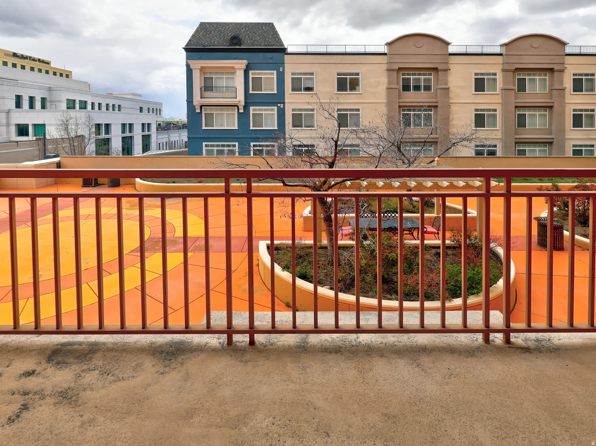 Rooftop patio featuring warm-toned paving with decorative patterns and an orange metal railing