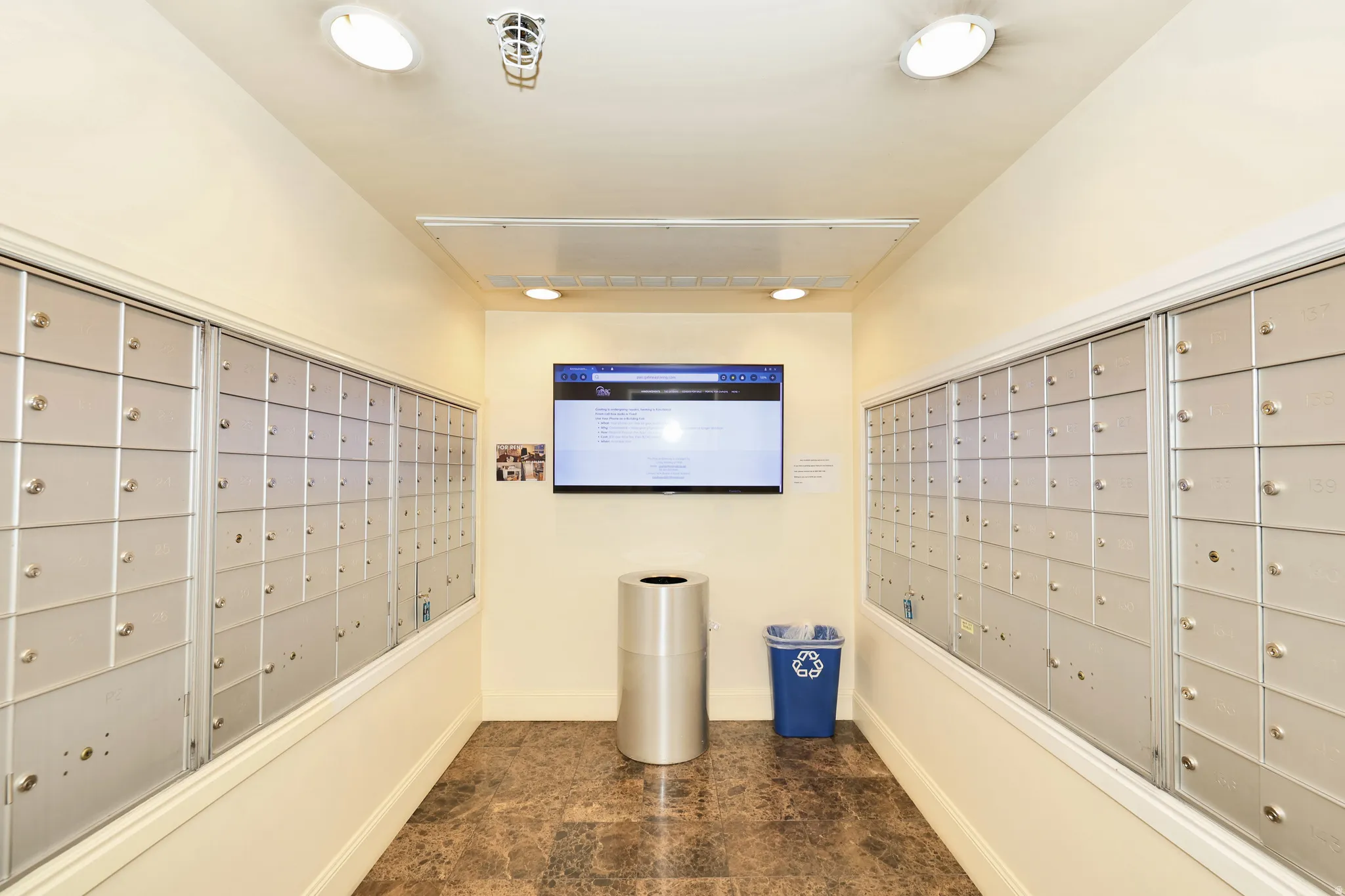 Mailroom featuring two walls of individual mailboxes and dark stone-finish flooring