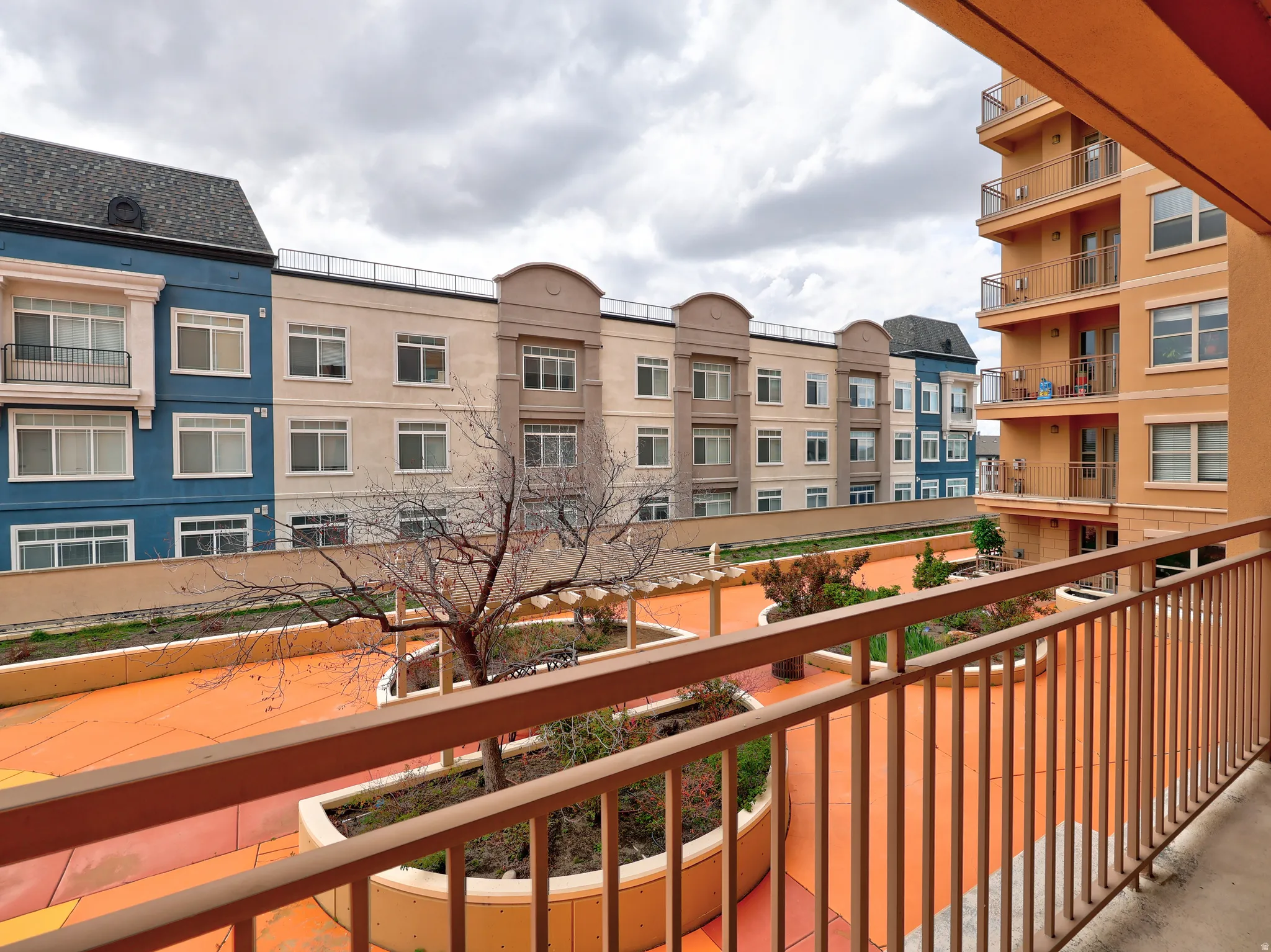 Private balcony overlooking a central courtyard with established trees and shrubbery
