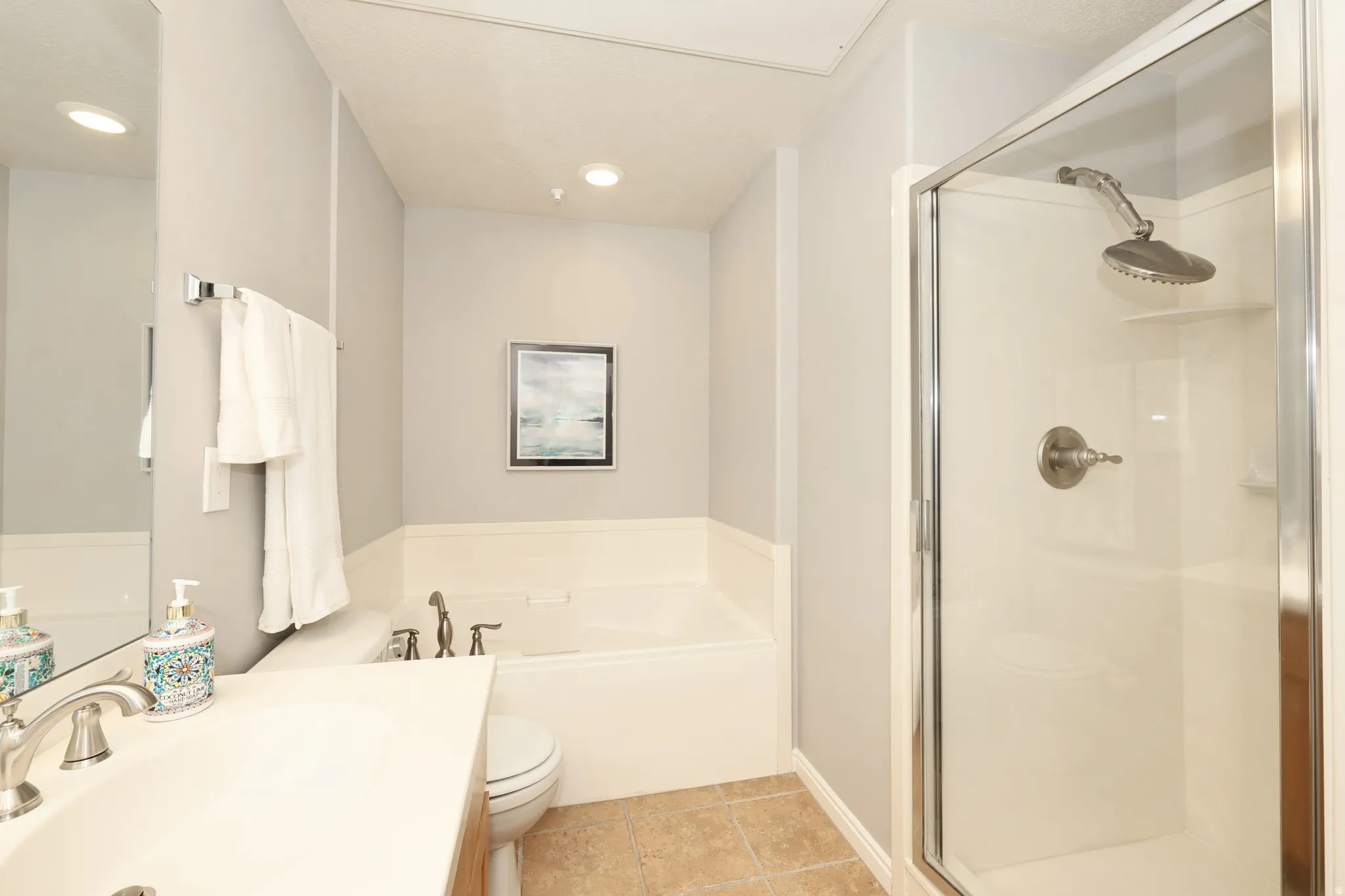 Full bathroom featuring a vanity with an integrated sink, a built-in tub, a glass-enclosed shower, and recessed lighting