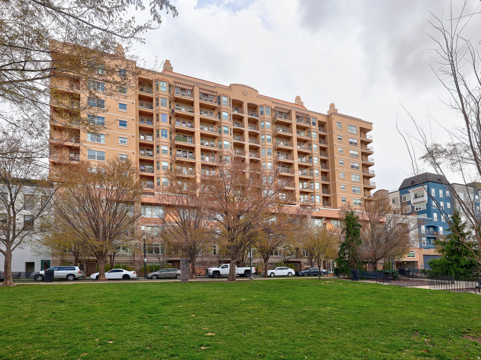 Multi-story building featuring numerous balconies, a terracotta-toned facade, and architectural detailing at the roofline