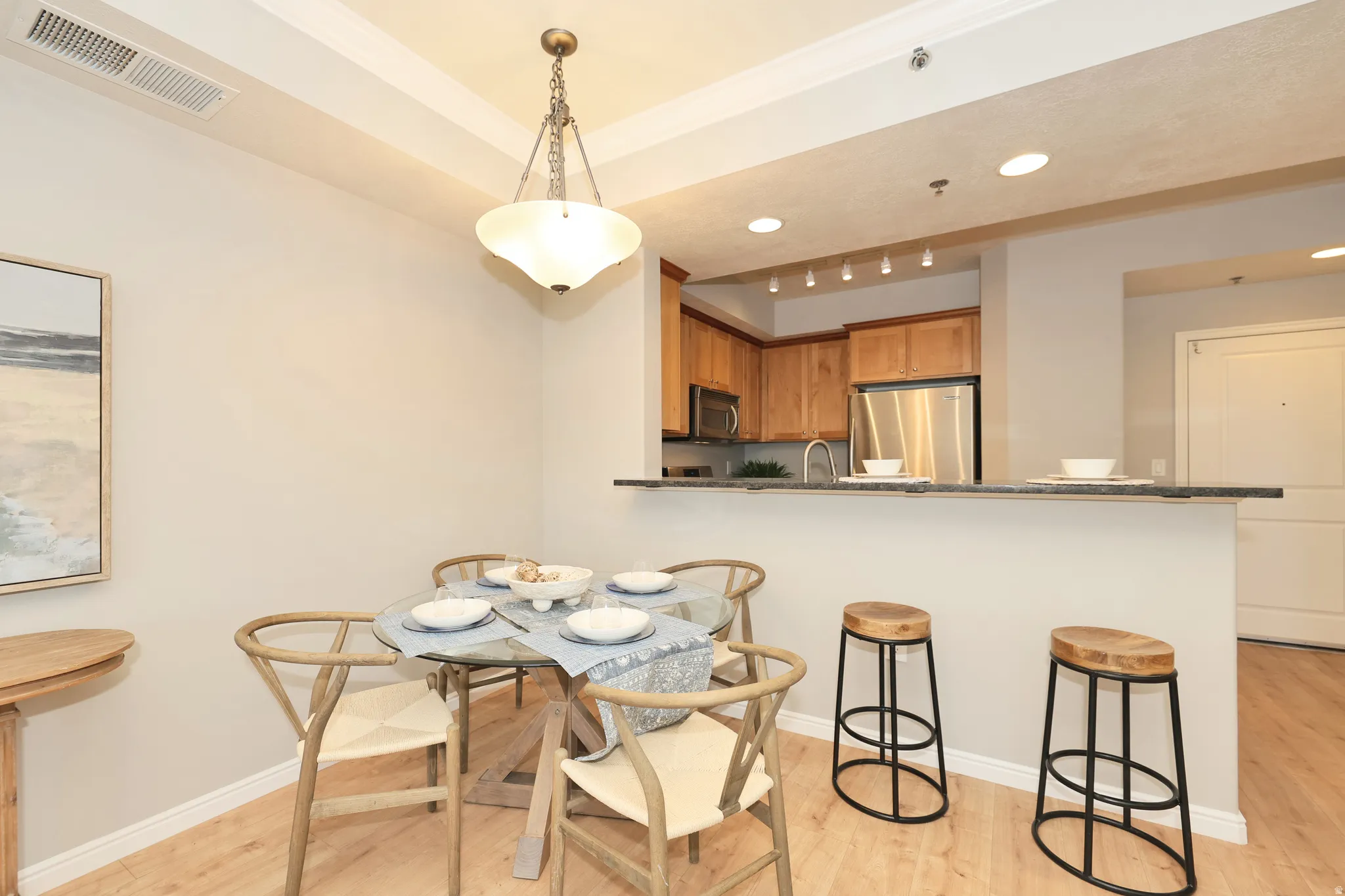 Dining area featuring wood-finish flooring, a tray ceiling, and a contemporary chandelier