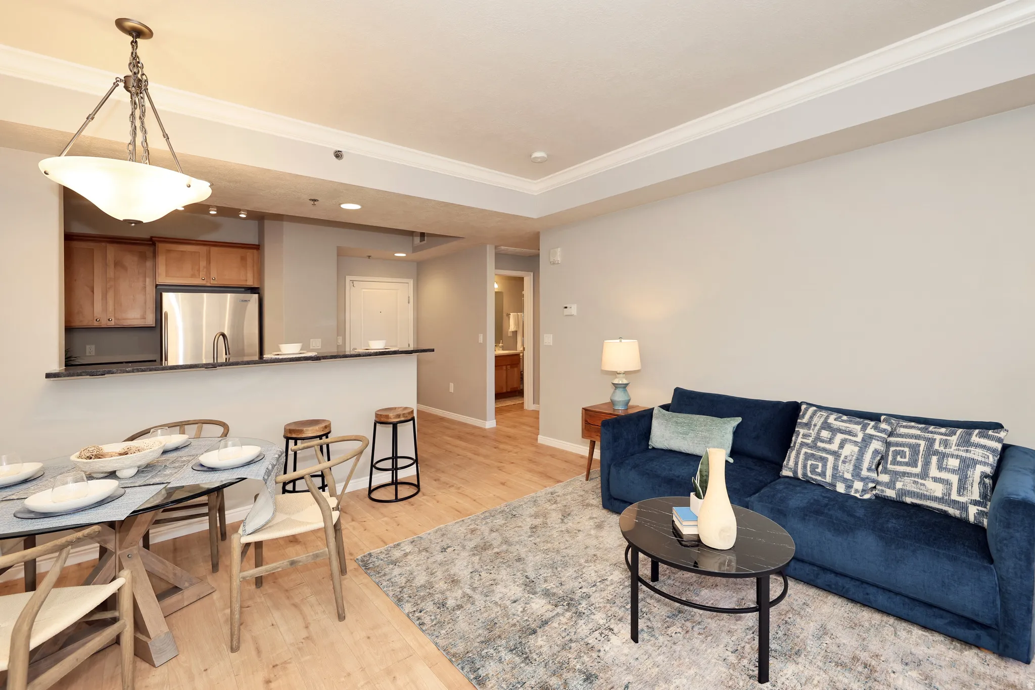 Open-concept living space featuring wood-finish flooring, crown molding, and recessed lighting