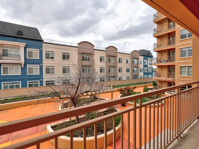 Private balcony overlooking a central courtyard with established trees and shrubbery
