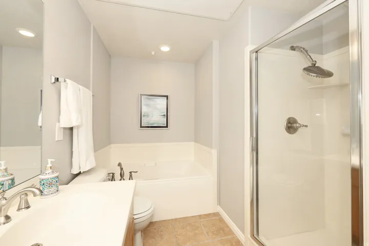Full bathroom featuring a vanity with an integrated sink, a built-in tub, a glass-enclosed shower, and recessed lighting