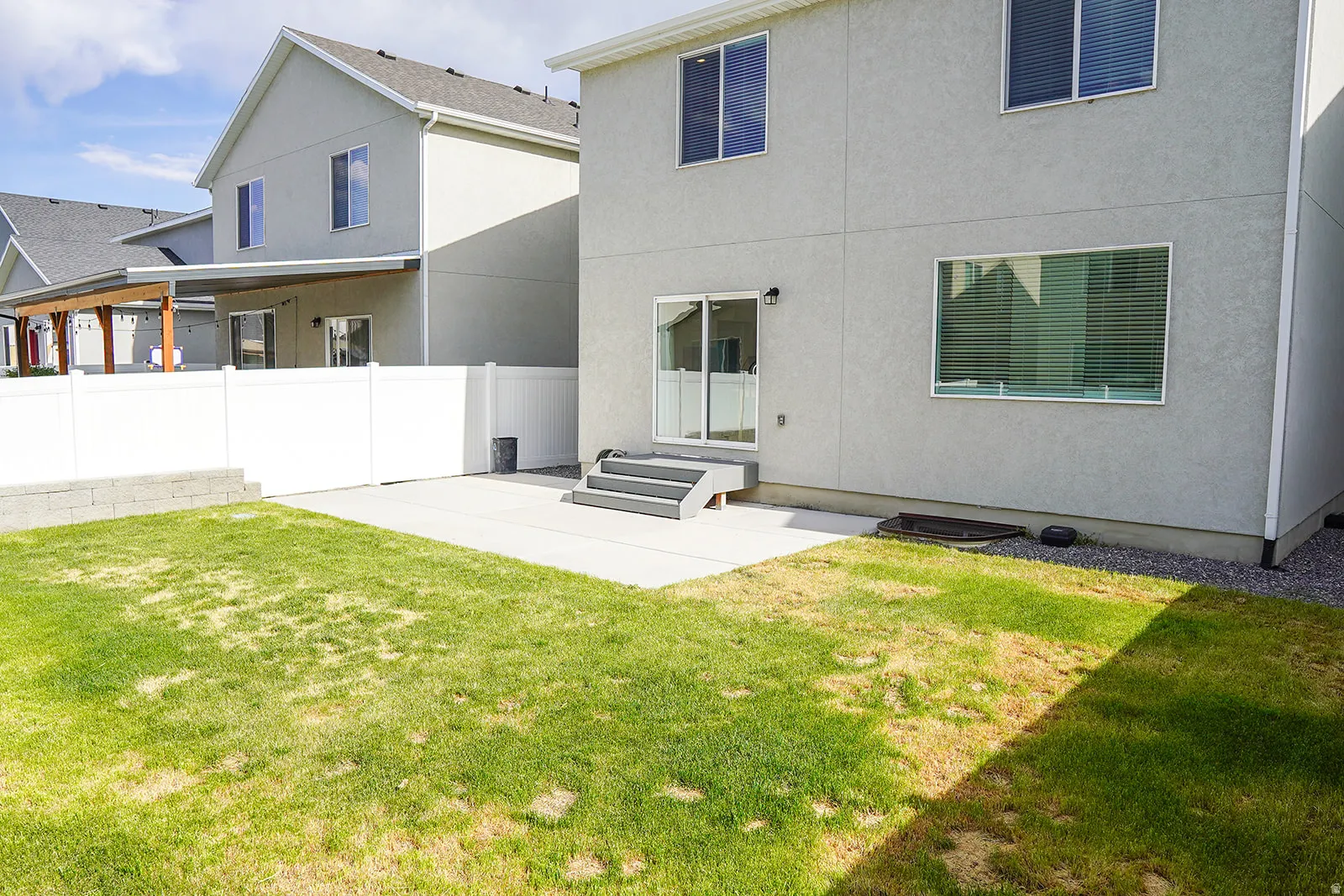 Rear exterior featuring a concrete patio, sliding glass door, and a three-step entry