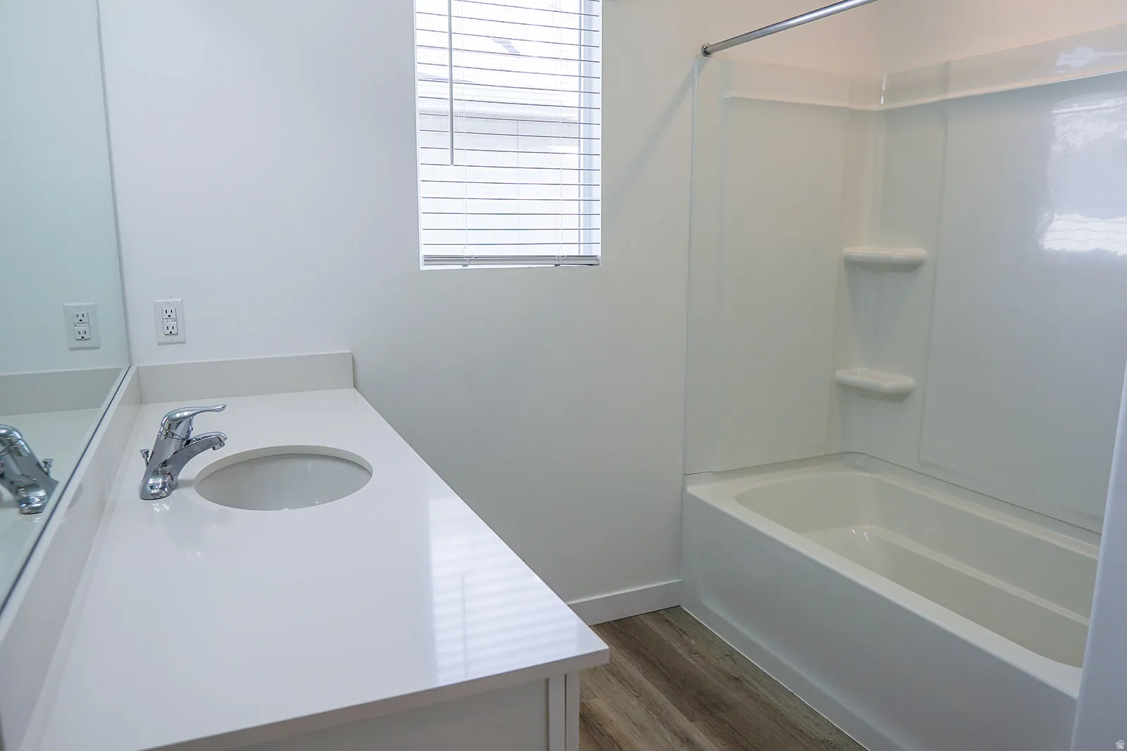 Bathroom featuring a white vanity with an integrated sink, polished chrome faucet, and expansive wall mirror