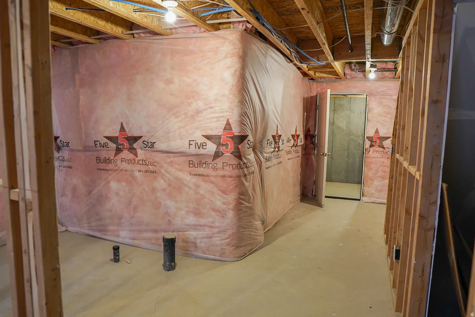 Unfinished basement space featuring exposed wood framing, concrete flooring, visible insulation, and overhead lighting