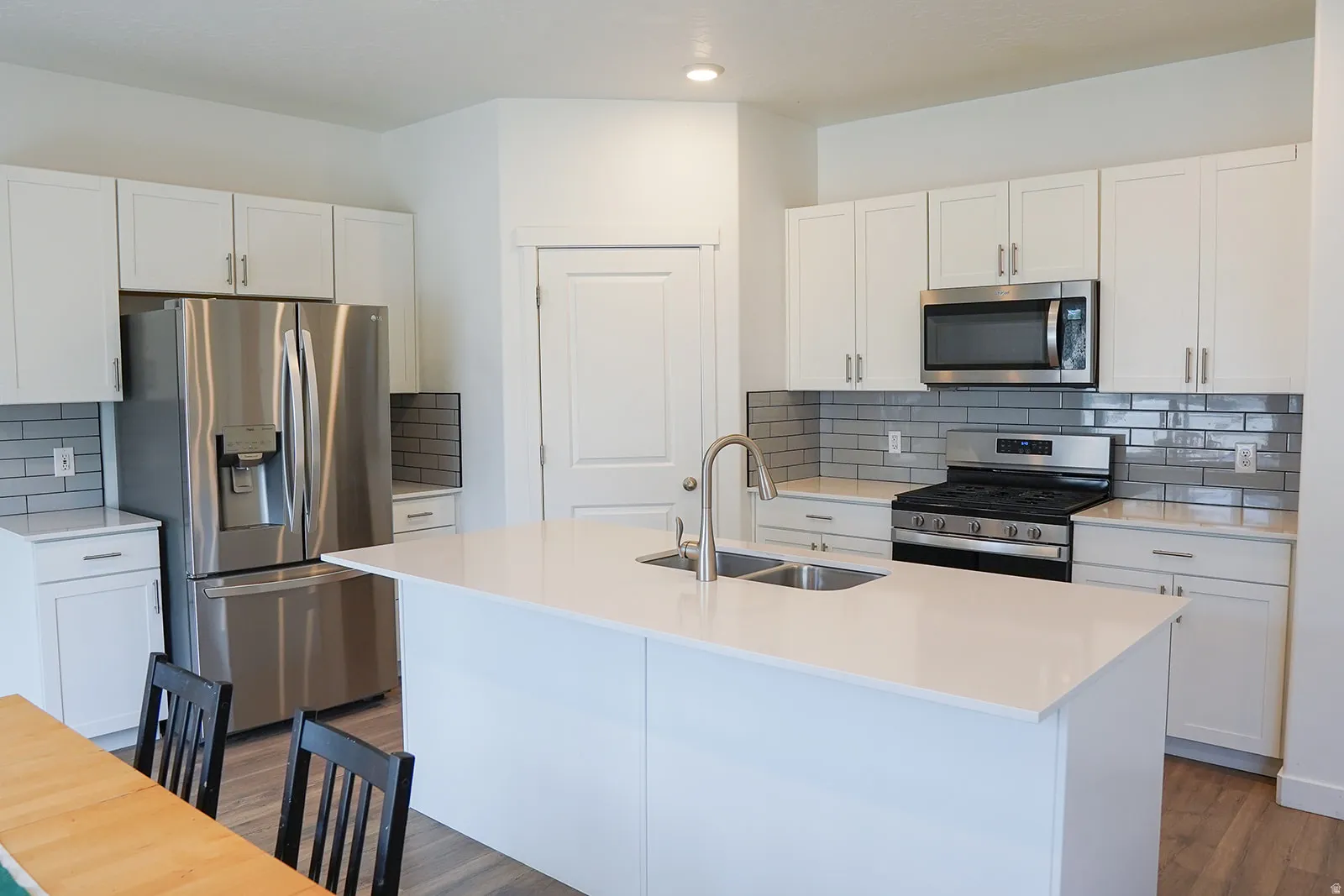 Modern kitchen featuring an expansive center island with an undermount dual-basin sink and a gooseneck faucet