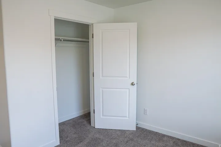 White interior door with brushed nickel hardware, opening to a closet featuring a single hanging rod