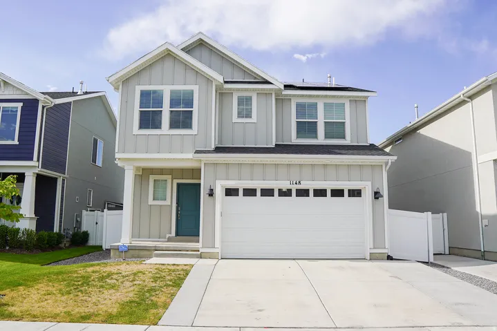 Modern two-story residence featuring light gray vertical siding with white trim accents and a contrasting teal entry door