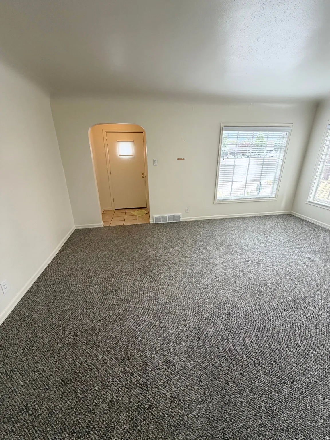 Carpeted living area featuring white walls and baseboards