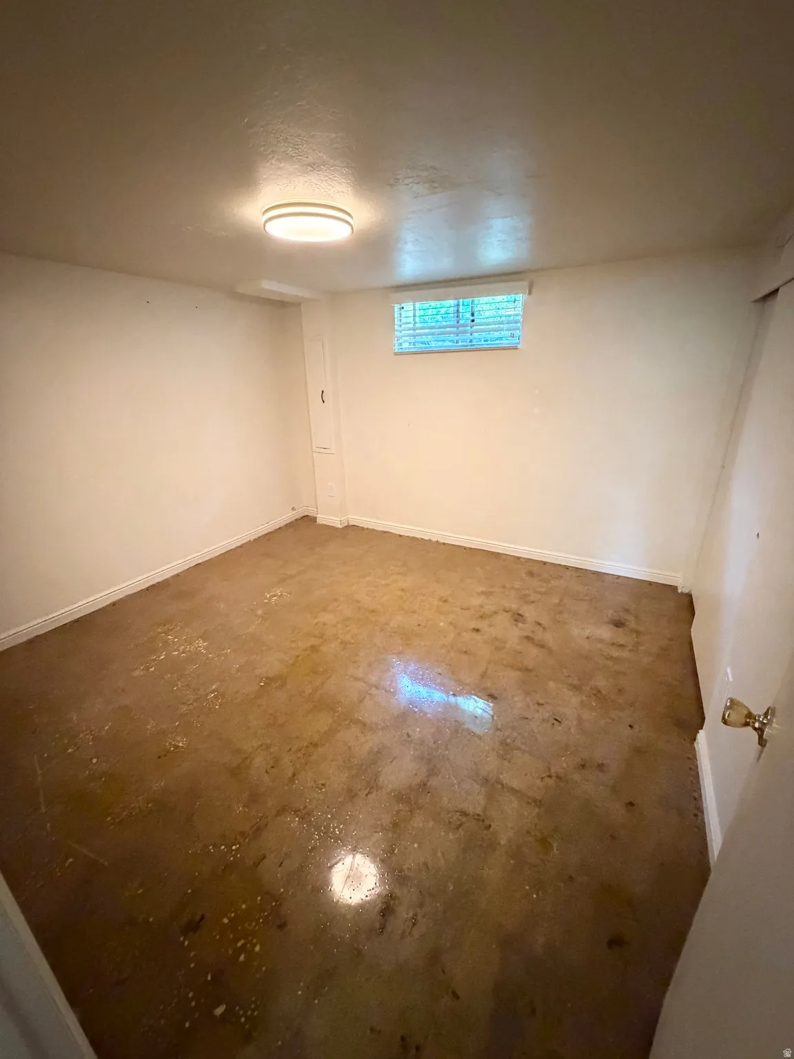 Room with light-colored walls, a ceiling-mounted light fixture, and a single window with horizontal blinds