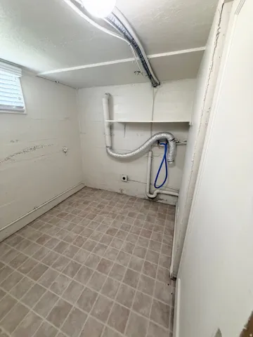 Utility room with tiled flooring, white walls, and a single window
