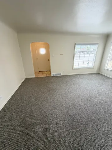 Carpeted living area featuring white walls and baseboards