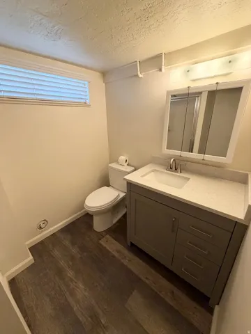 Bathroom featuring a gray vanity with a single sink, light-toned countertop, and brushed nickel hardware