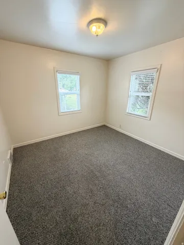 Neutral wall paint, two windows with blinds, and recessed lighting