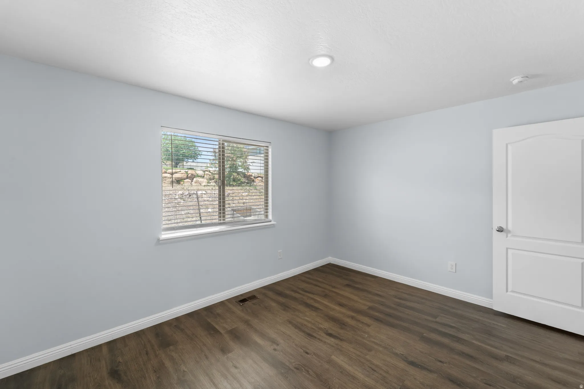 Interior room featuring wood-finish flooring, light blue walls, and a recessed ceiling light