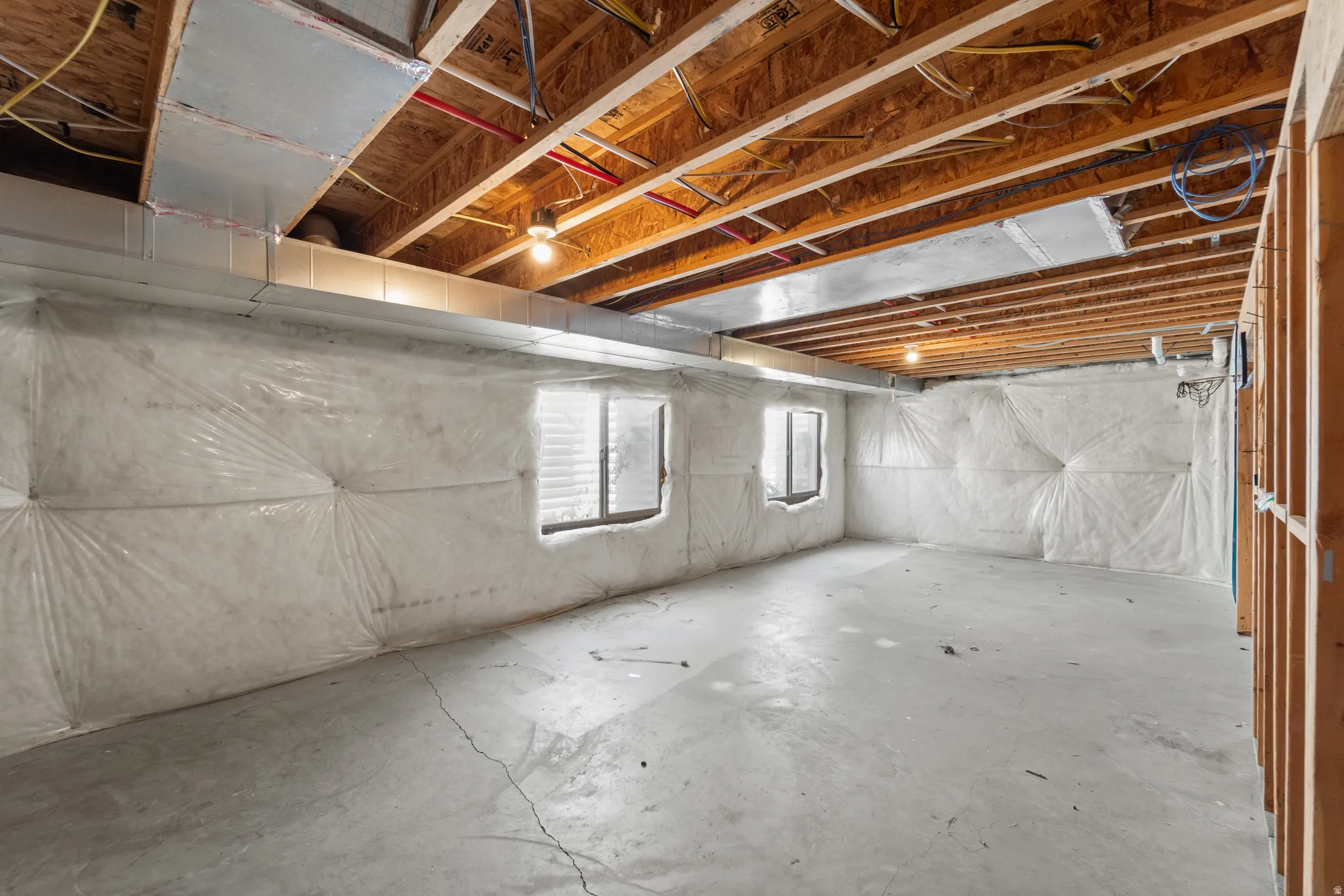 Unfinished basement offering exposed ceiling joists, concrete flooring, and insulated walls