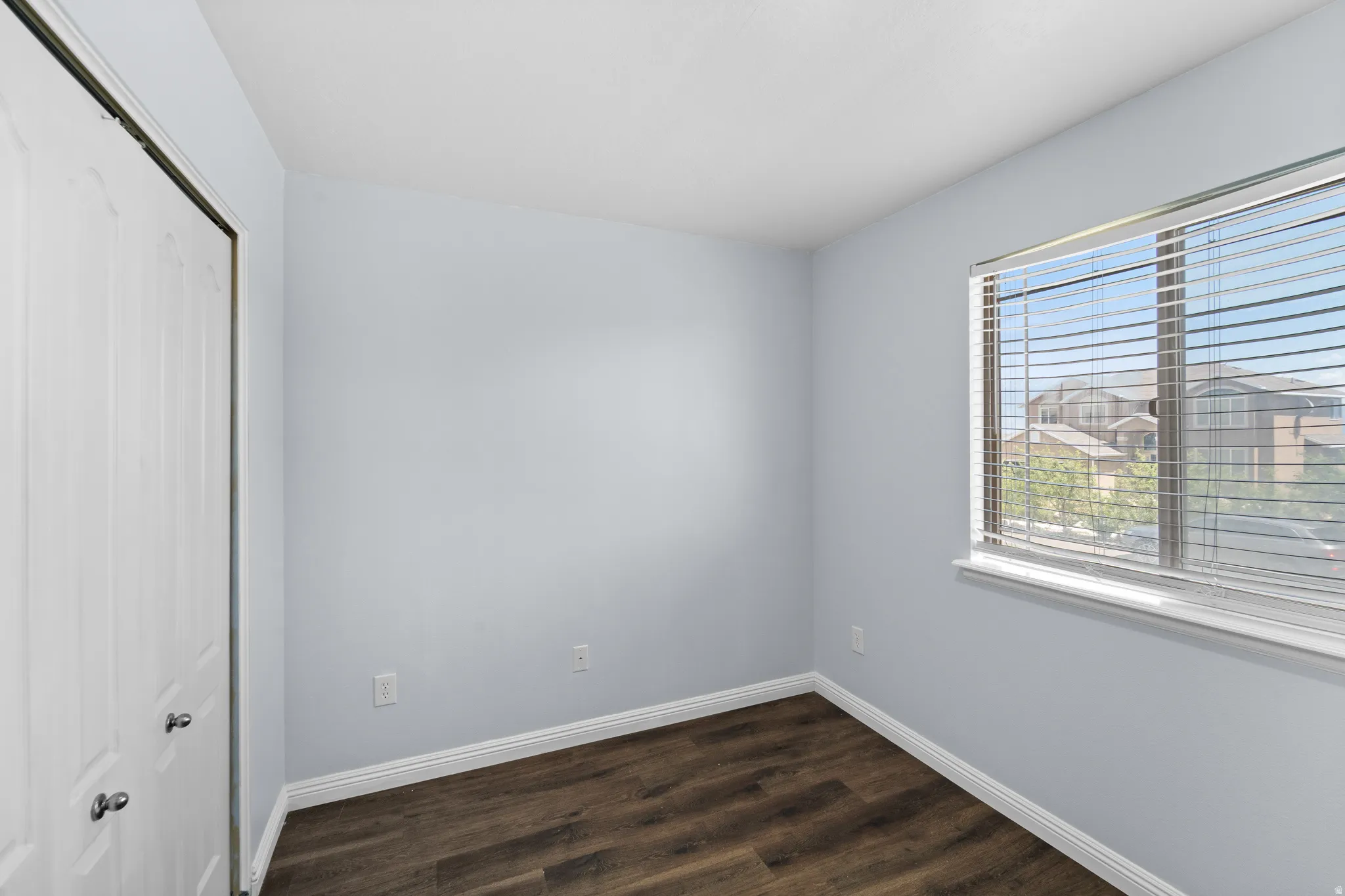 Room featuring wood-finish flooring, light gray wall paint, and white trim