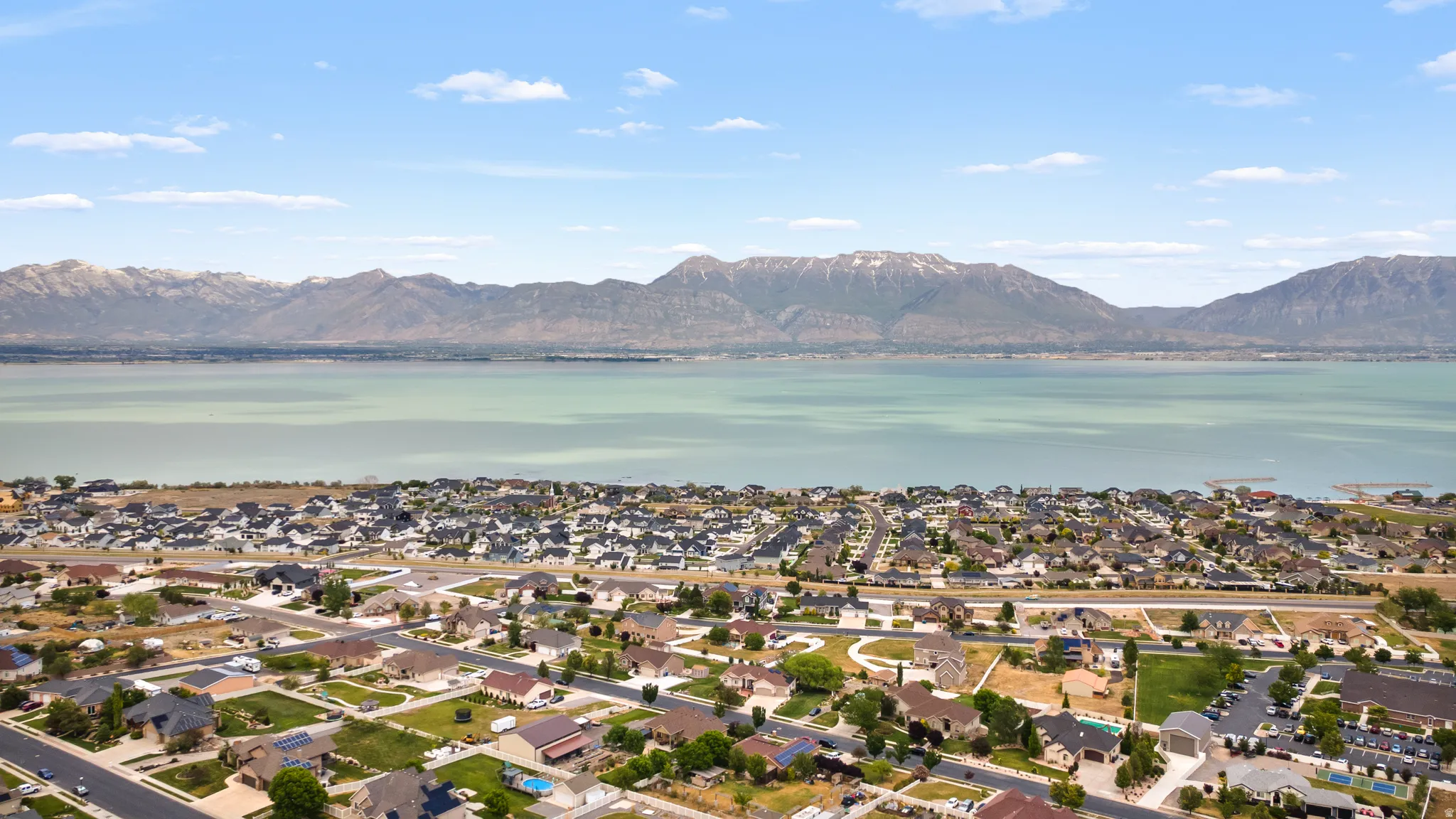 Aerial perspective showcasing a residential community with a large body of water and distant mountains