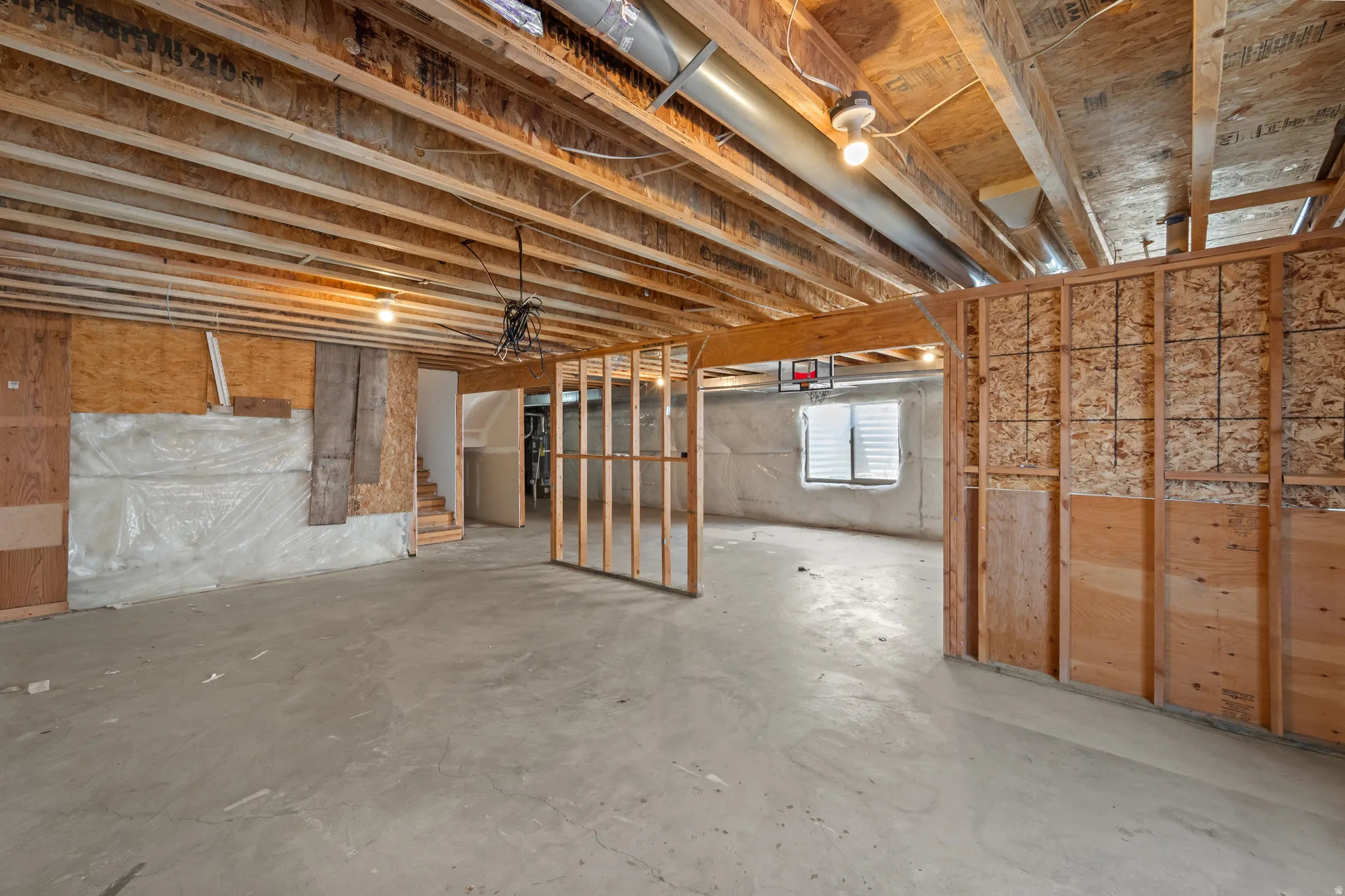 Unfinished basement offering expansive concrete flooring and exposed ceiling joists