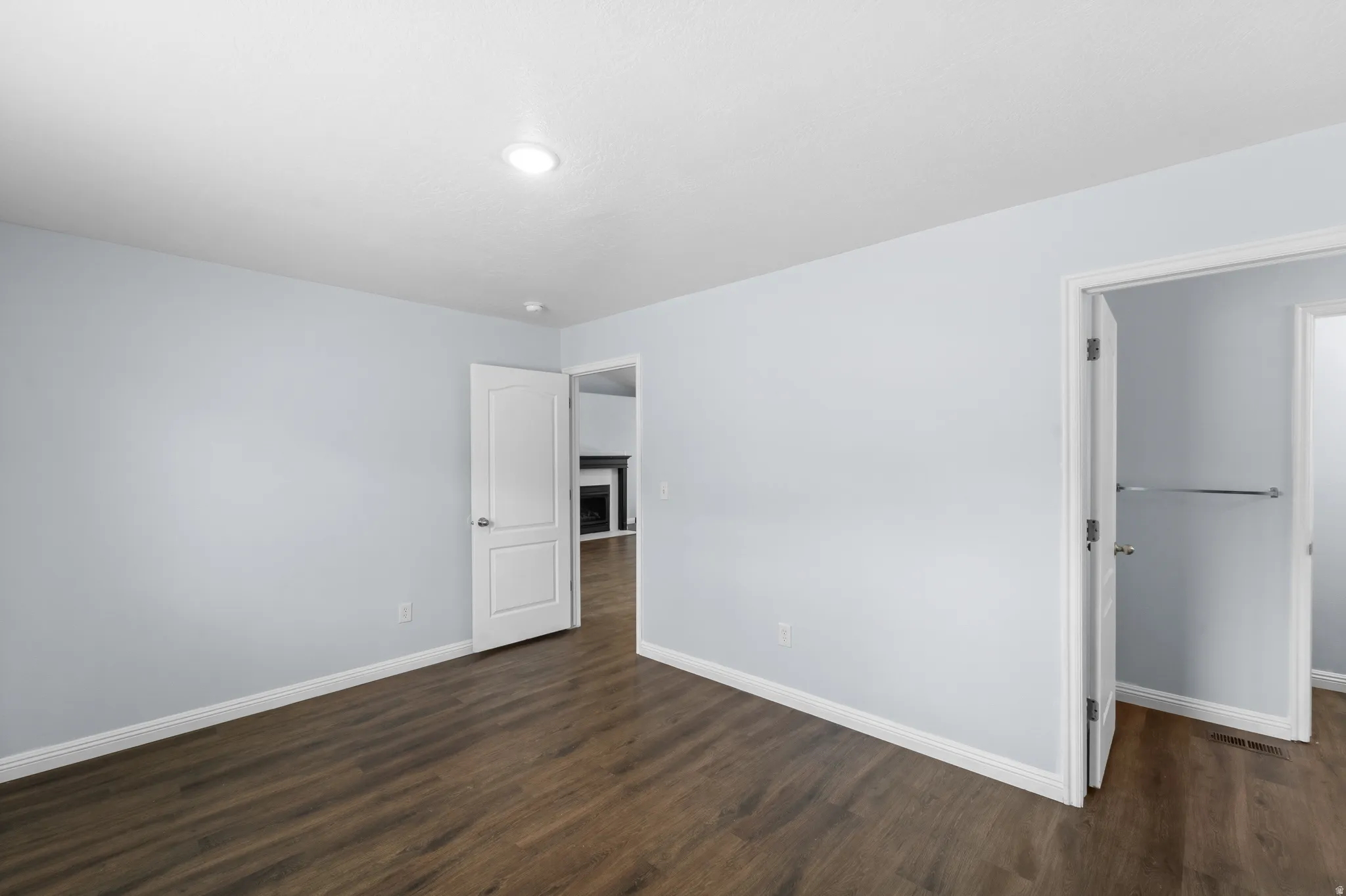Spacious room with wood-finish flooring, light blue walls, and white trim