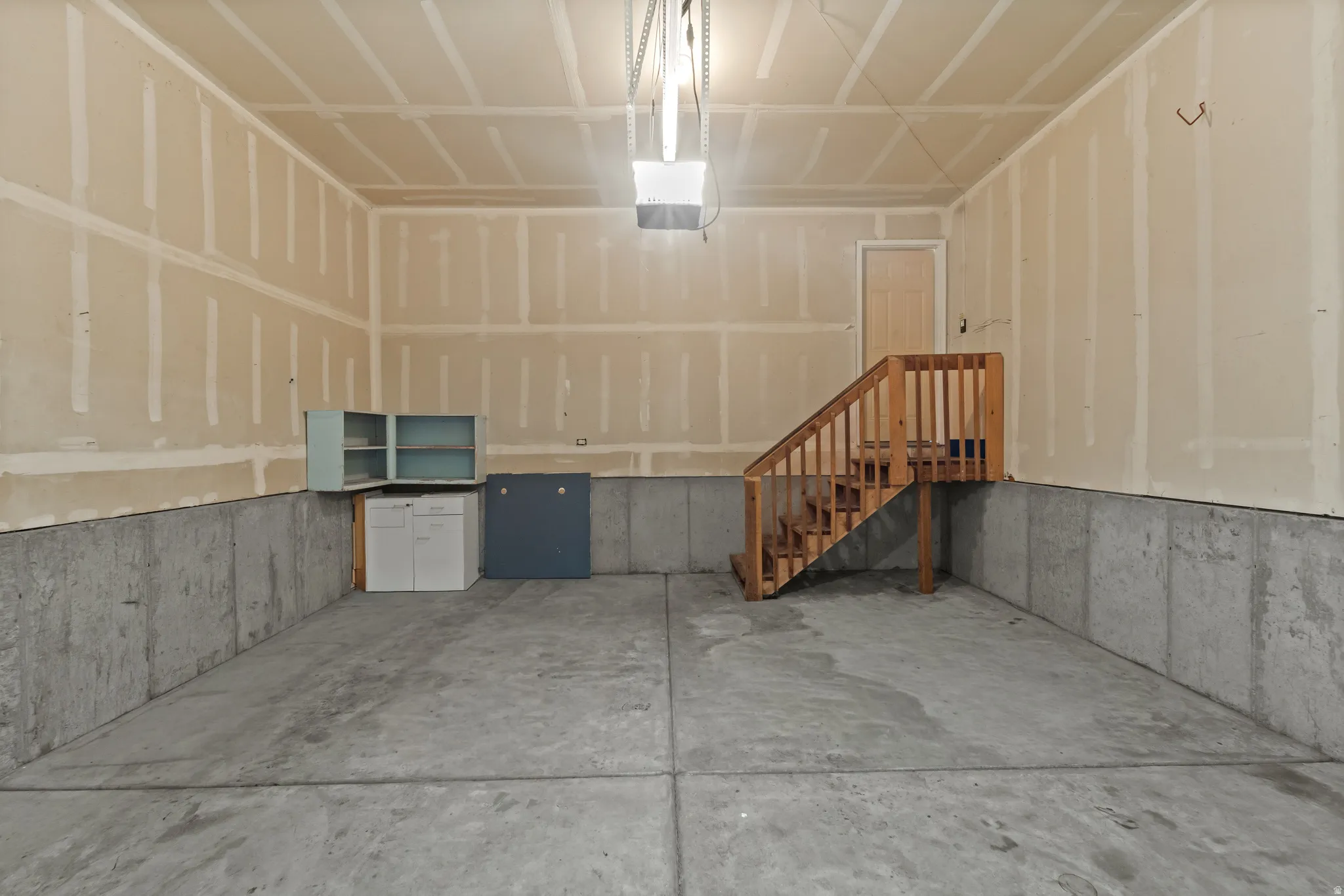 Spacious garage with concrete flooring and a finished wood staircase