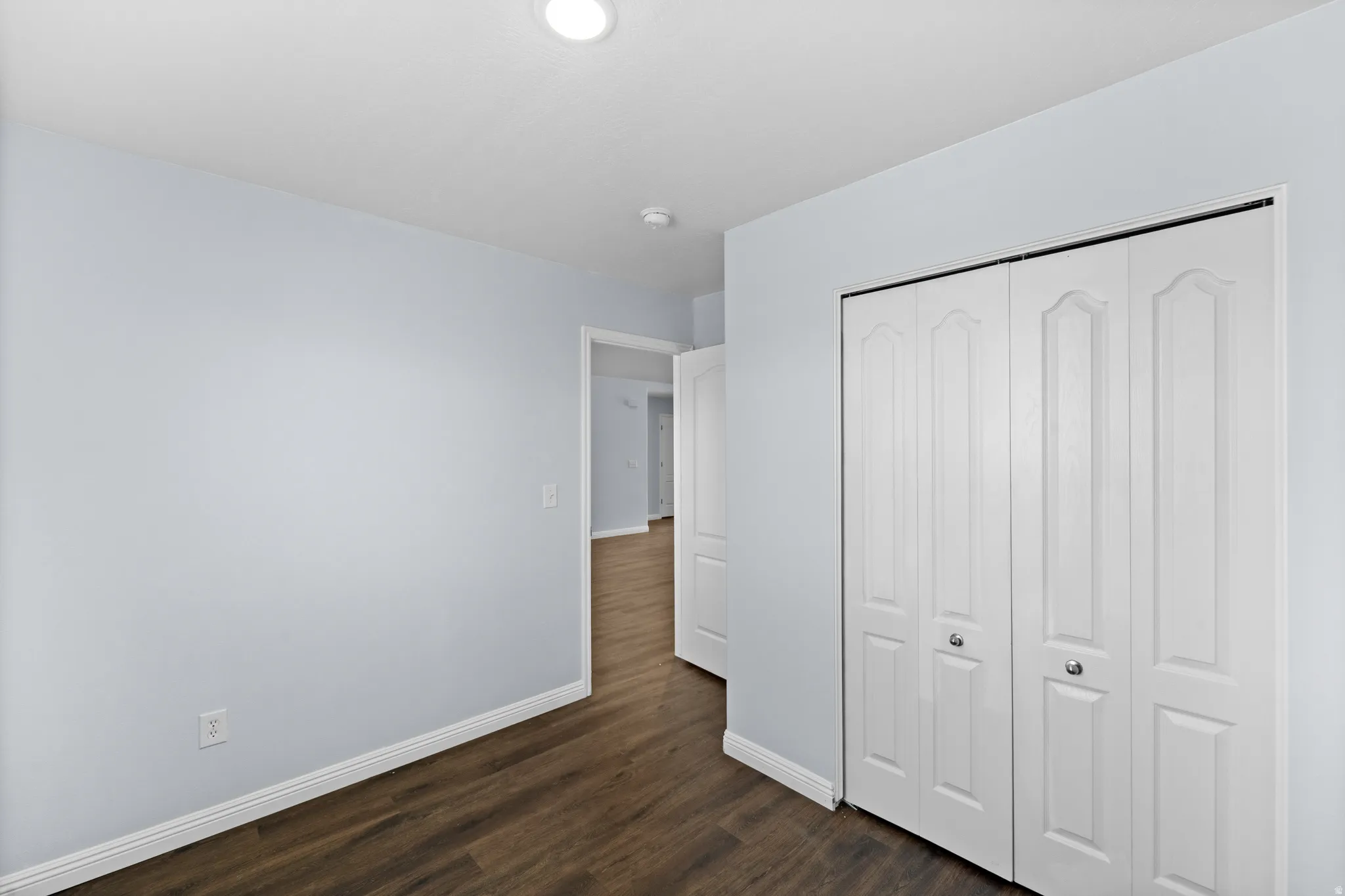 Interior room featuring wood-finish flooring, light gray walls, white baseboards, and a recessed ceiling light