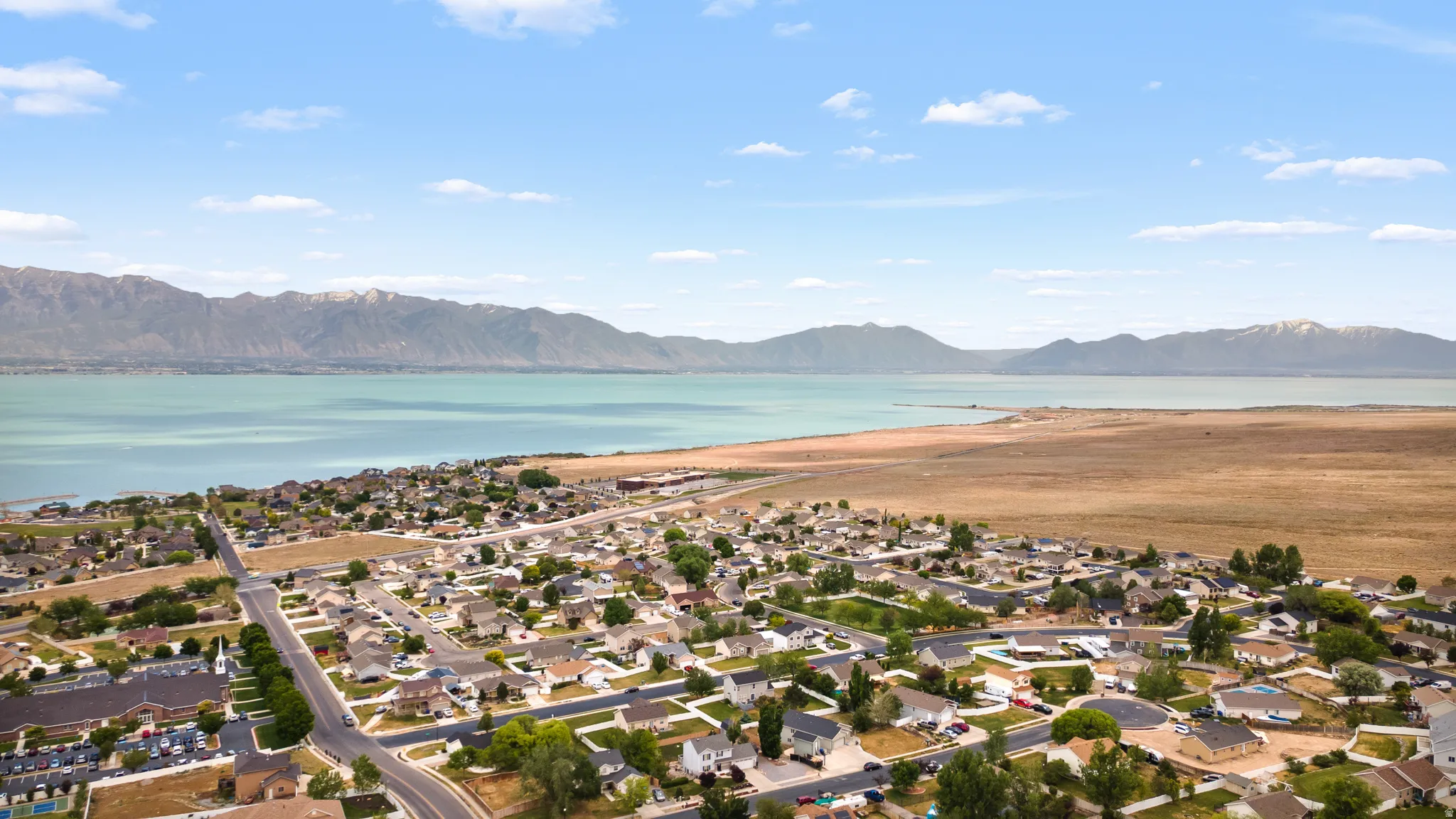 Aerial perspective showcasing a residential community situated along a body of water, with distant mountains forming a natural backdrop