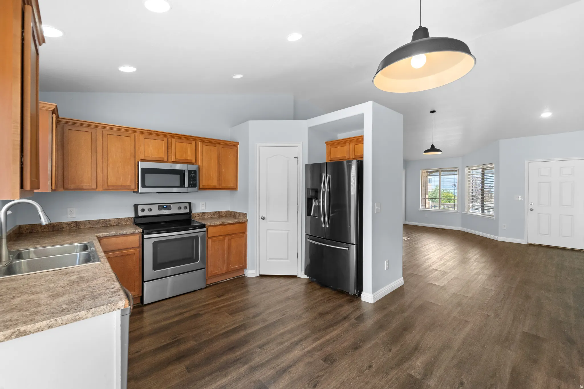 Kitchen and living area featuring wood-finish flooring, recessed lighting, and a stainless steel appliance package