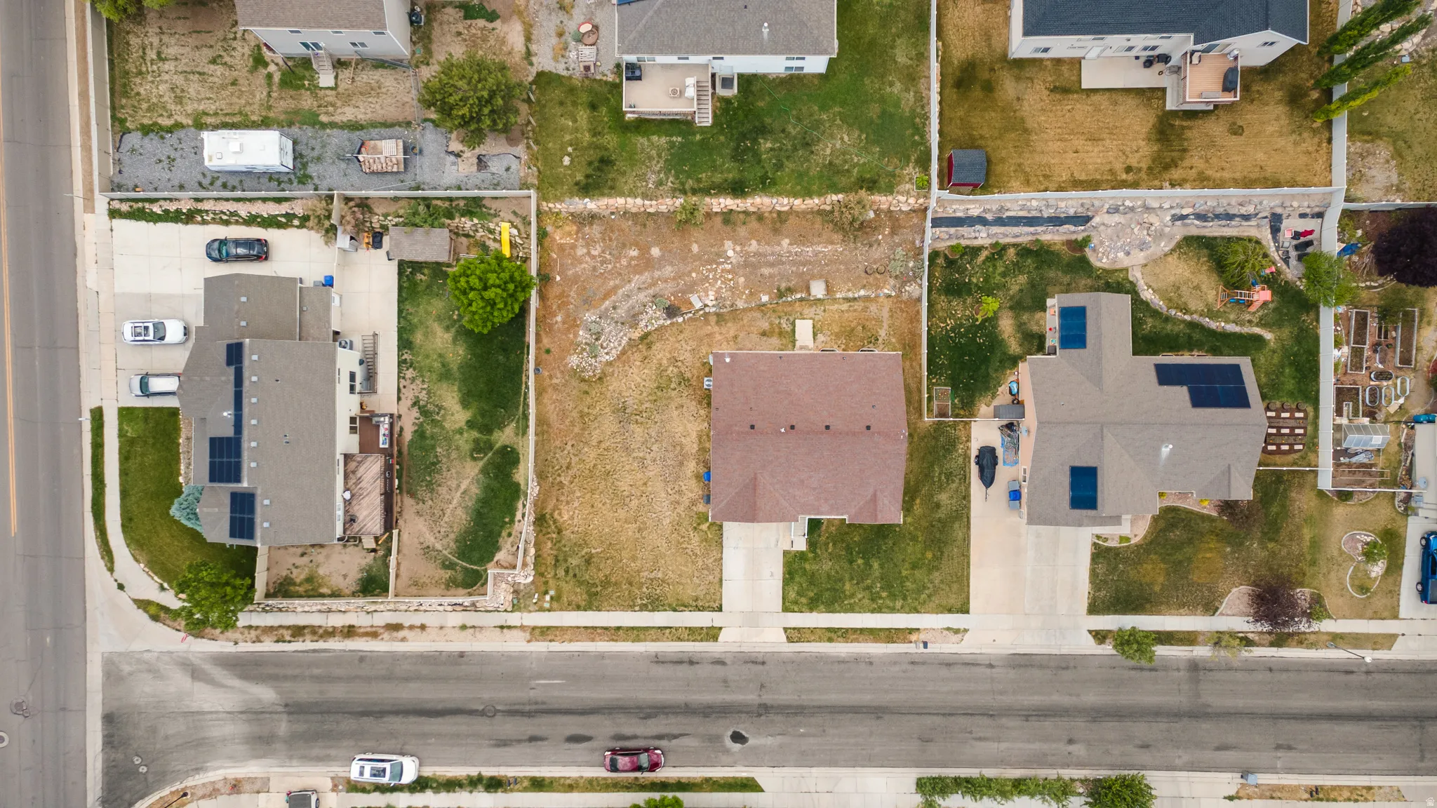 Expansive residential property featuring a large grass lawn, paved driveway, and established landscaping elements