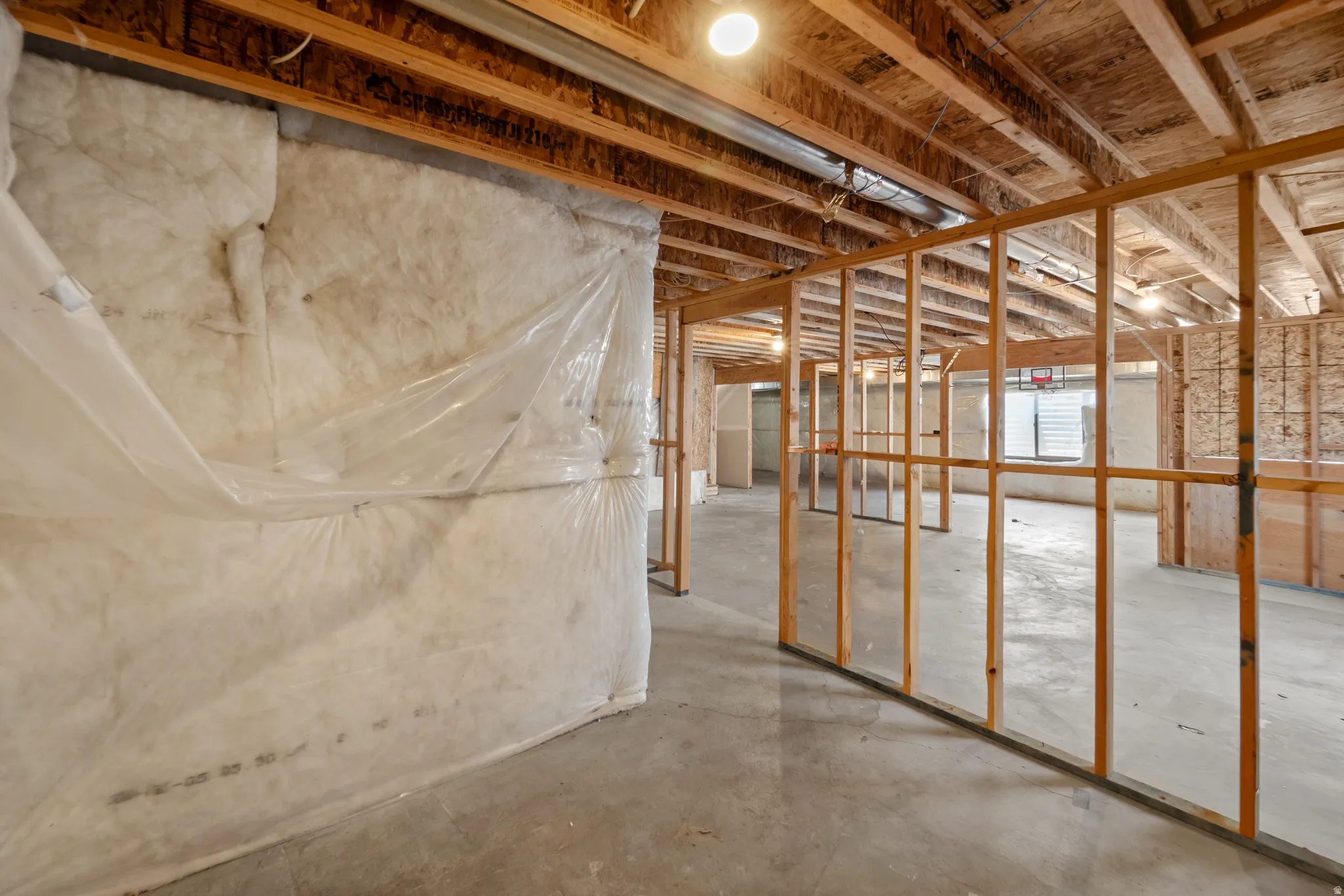 Unfinished lower level featuring exposed wood framing, concrete flooring, and visible insulation