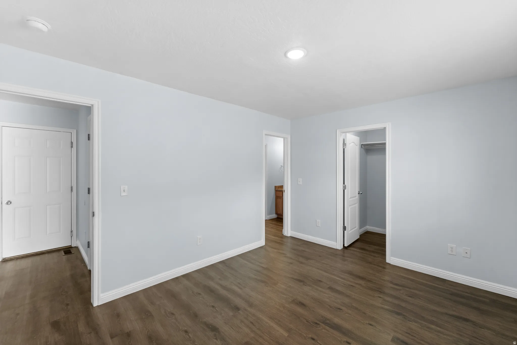 Interior room featuring wood-finish flooring, light blue painted walls, white baseboards, and white trim