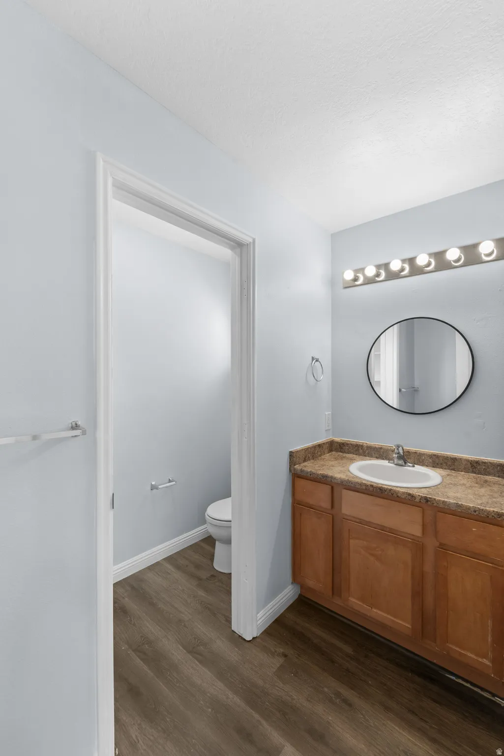 Bathroom vanity featuring a single basin sink, wood cabinetry, and a stone-finish countertop