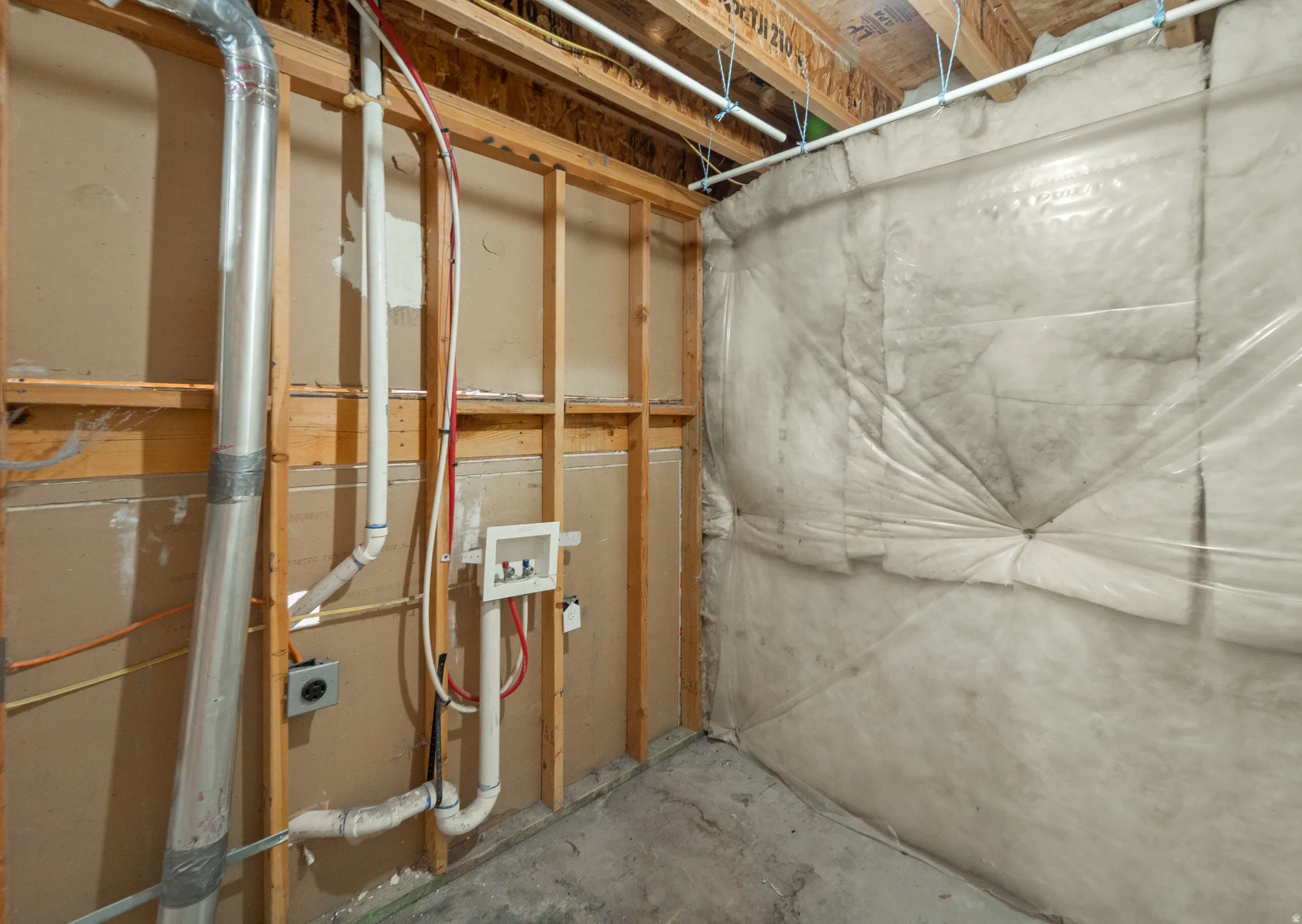Unfinished space featuring visible framing, insulation, and concrete flooring