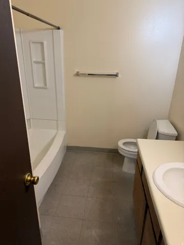 Bathroom featuring a white tub and shower combination, a toilet, and a vanity with a built-in sink