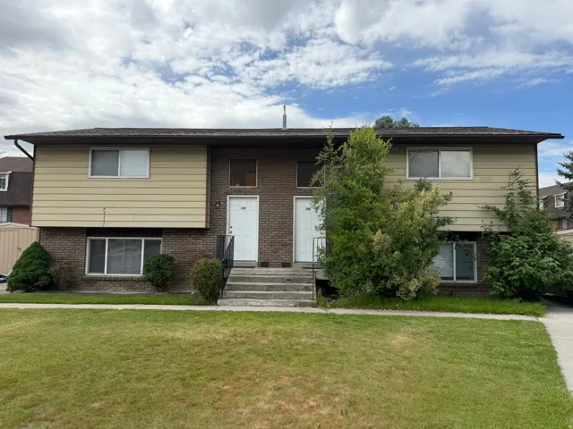 Duplex property featuring a brick and siding exterior, multiple windows, and separate entryways