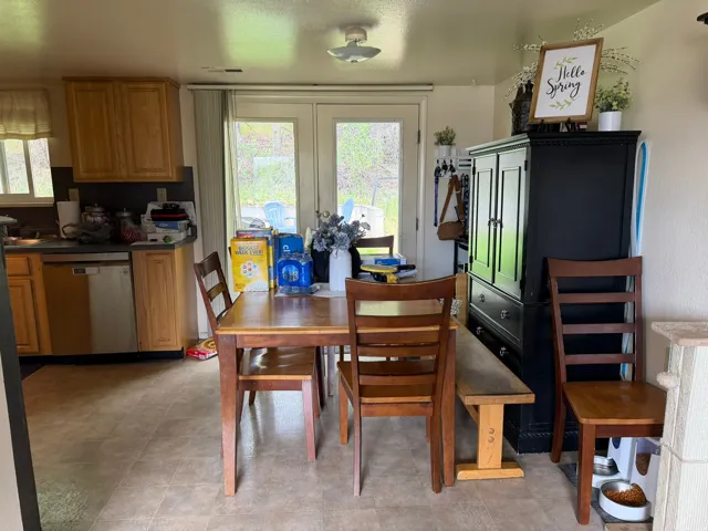 Eat-in kitchen featuring light wood cabinetry, a stainless steel dishwasher, and neutral-toned flooring