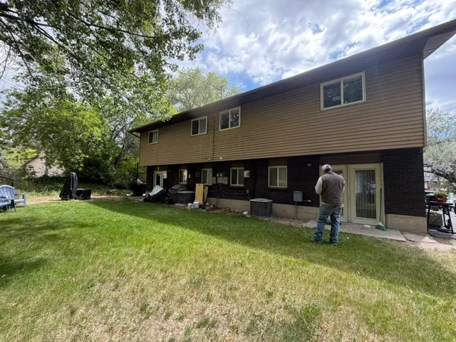 Two-story exterior featuring tan siding and dark brick lower facade